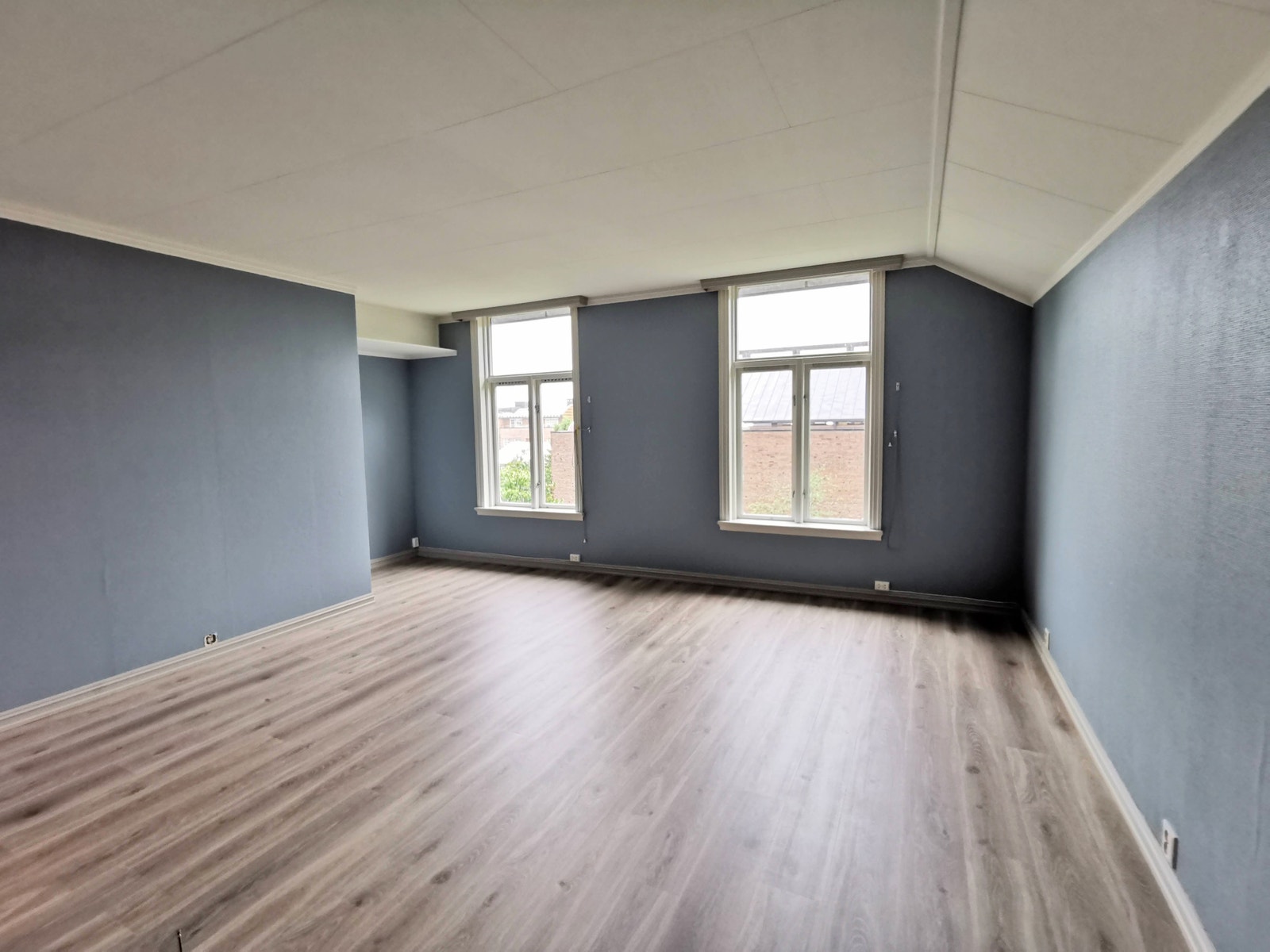 Stue. Tidligere leietaker har hatt kontorpult i nisjen til venstre. Det er vannbåren varme i gulvet og utvendige markiser. Galleribilde