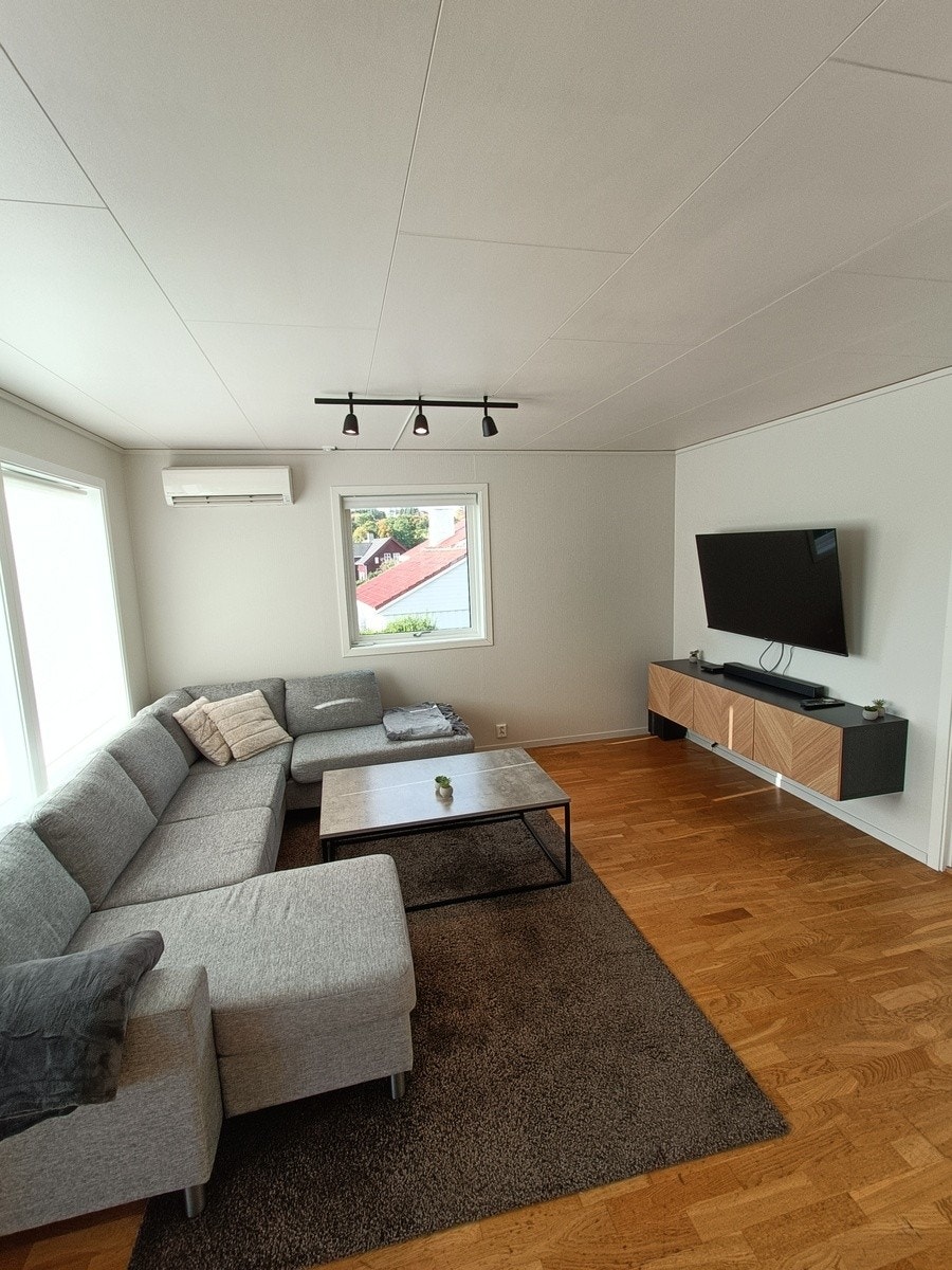 Stue med vegghengt smart TV samt varmepumpe Galleribilde