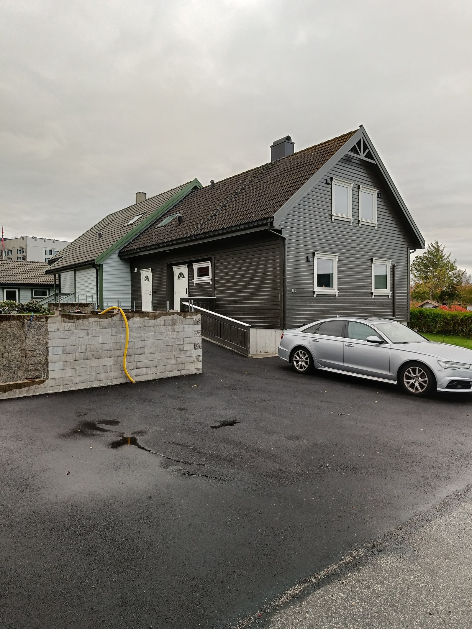 Parkeringsplass. Huset er malt i mørke farger og ny asfalt er lagt i gårdsrommet Galleribilde