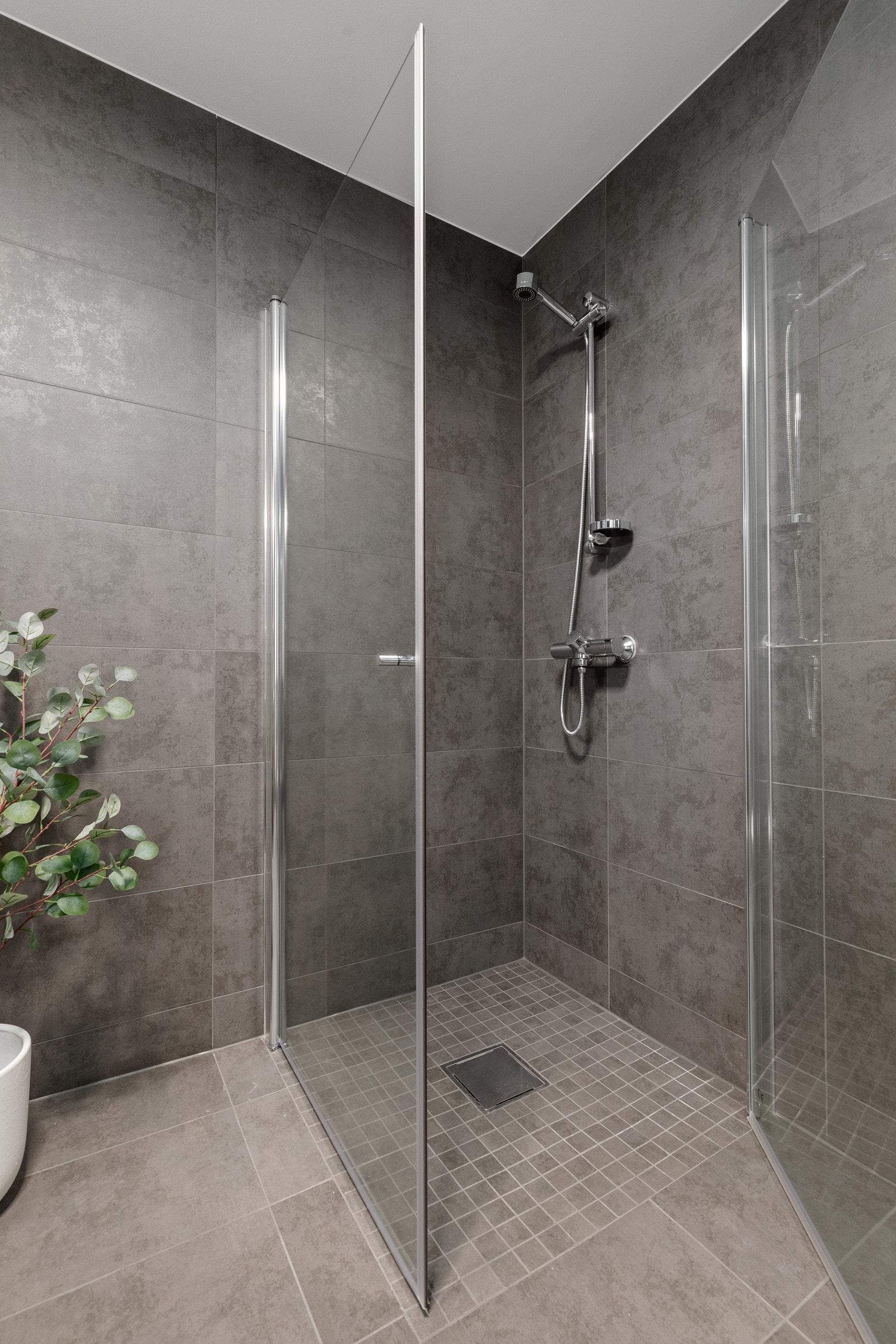 Dusjhjørne med glasveggar og vegghengt toalett. Galleribilde