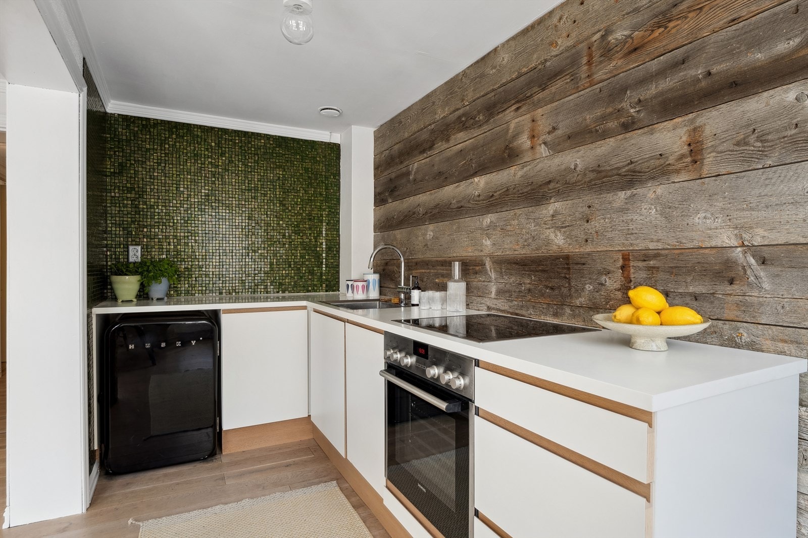 Stilren dansk-designet kjøkkeninnredning (JKE) med sømløs og eksklusiv Corian benkeplate. Det er et eksempel på påkostede detaljer i denne lille leiligheten. Galleribilde