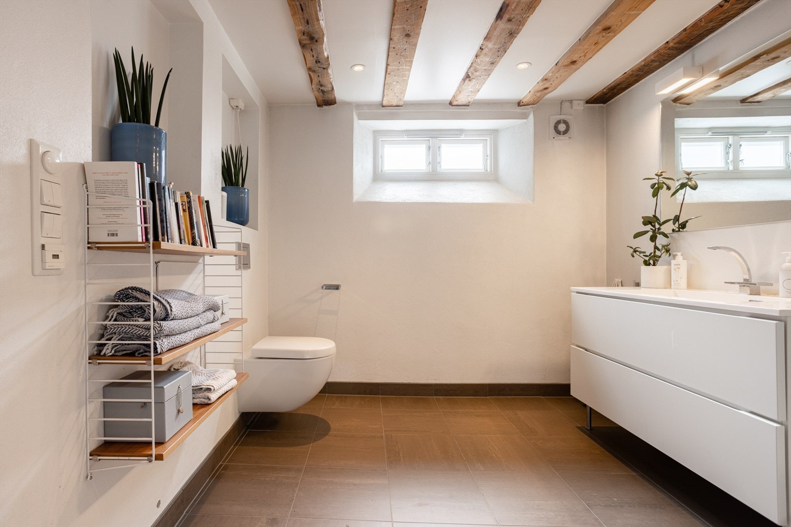 Baderom fra 2012. Badet er utstyrt med vegghengt wc, servant med skuffer under, dusj i hjørne med glassvegg/glassdør og håndkletørker. Galleribilde