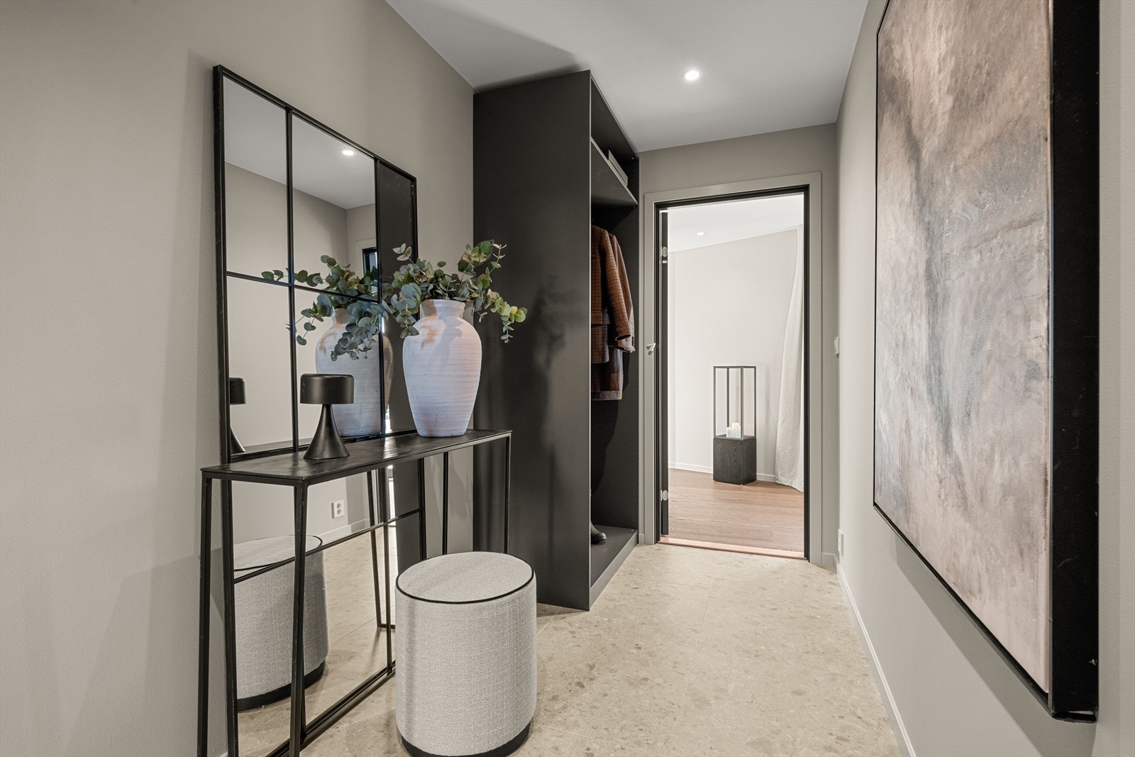 Hallen er romslig og innbydende, med flislagt gulv og gulvvarme. Veggene er malt i moderne fargetoner, og stemningsfull belysning fra downlights i taket skaper en behagelig atmosfære. Galleribilde