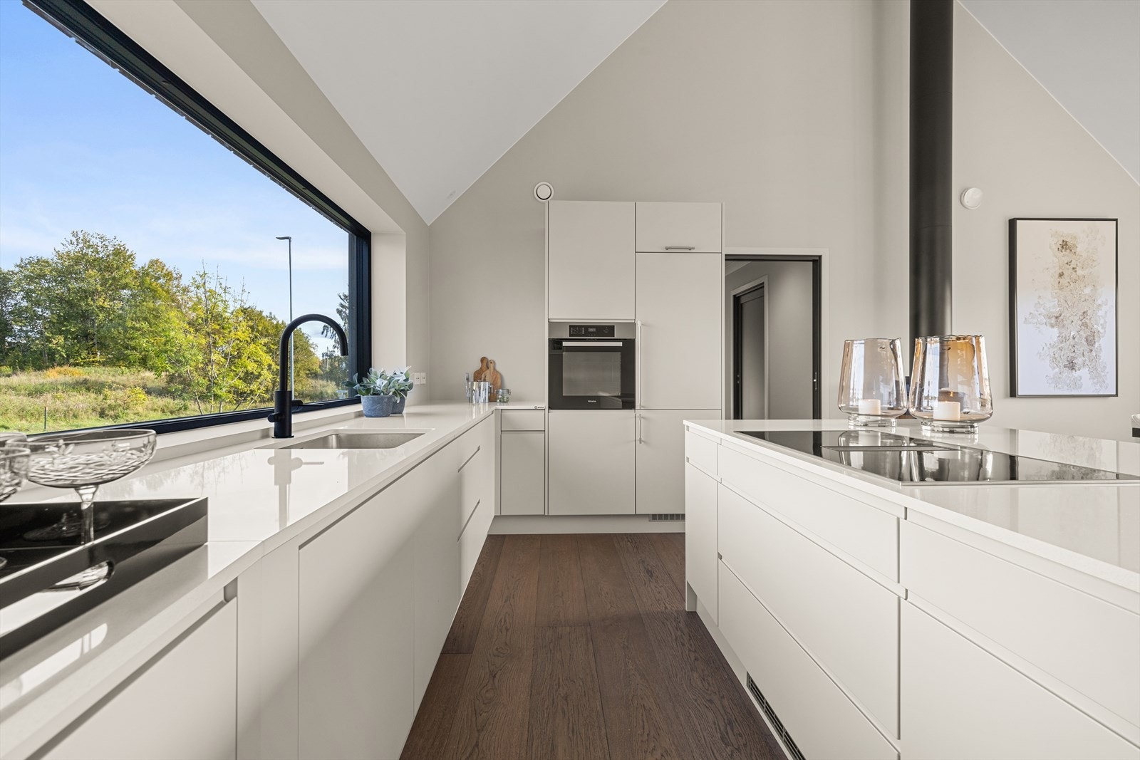 Innredningen er plassert langs to vegger, kombinert med en kjøkkenøy som gir rikelig med arbeidsplass og oppbevaringsmuligheter. Galleribilde