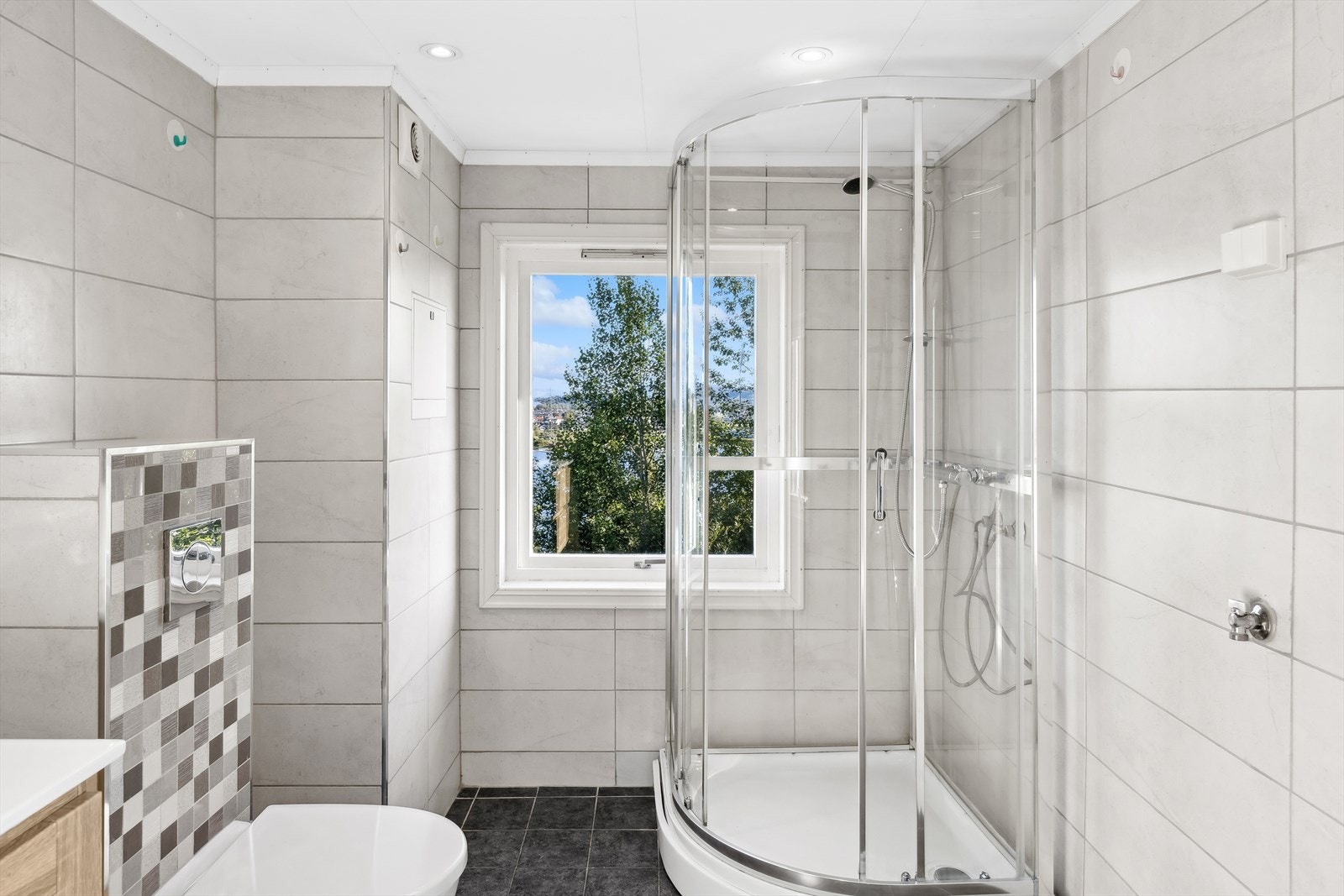 Badet har innredning med nedfelt servant, veggmontert toalett og dusjkabinett. Galleribilde
