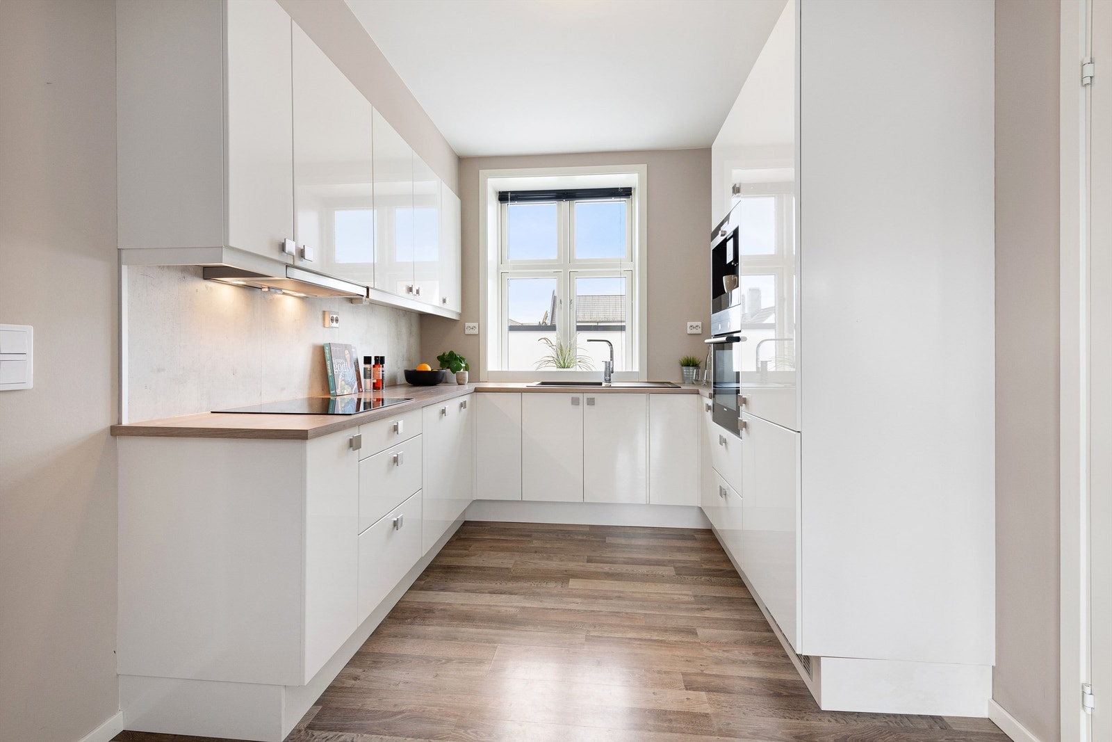 Kjøkkeninnredning fra HTH med hvite glatte fronter og benkeplate av laminat. Integrerte hvitevarer Galleribilde