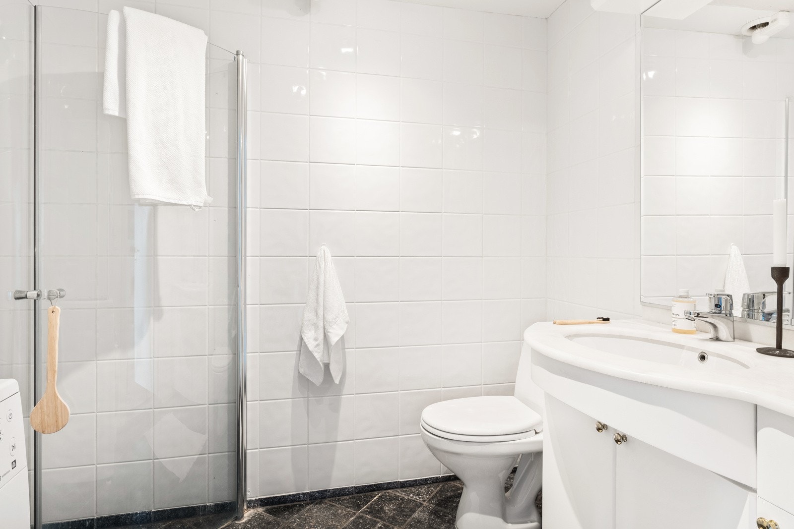 Badet er helfliset og har en slett malt himling. Det er innredet med toalett, dusj med glassvegger og baderomsmøbler. Galleribilde