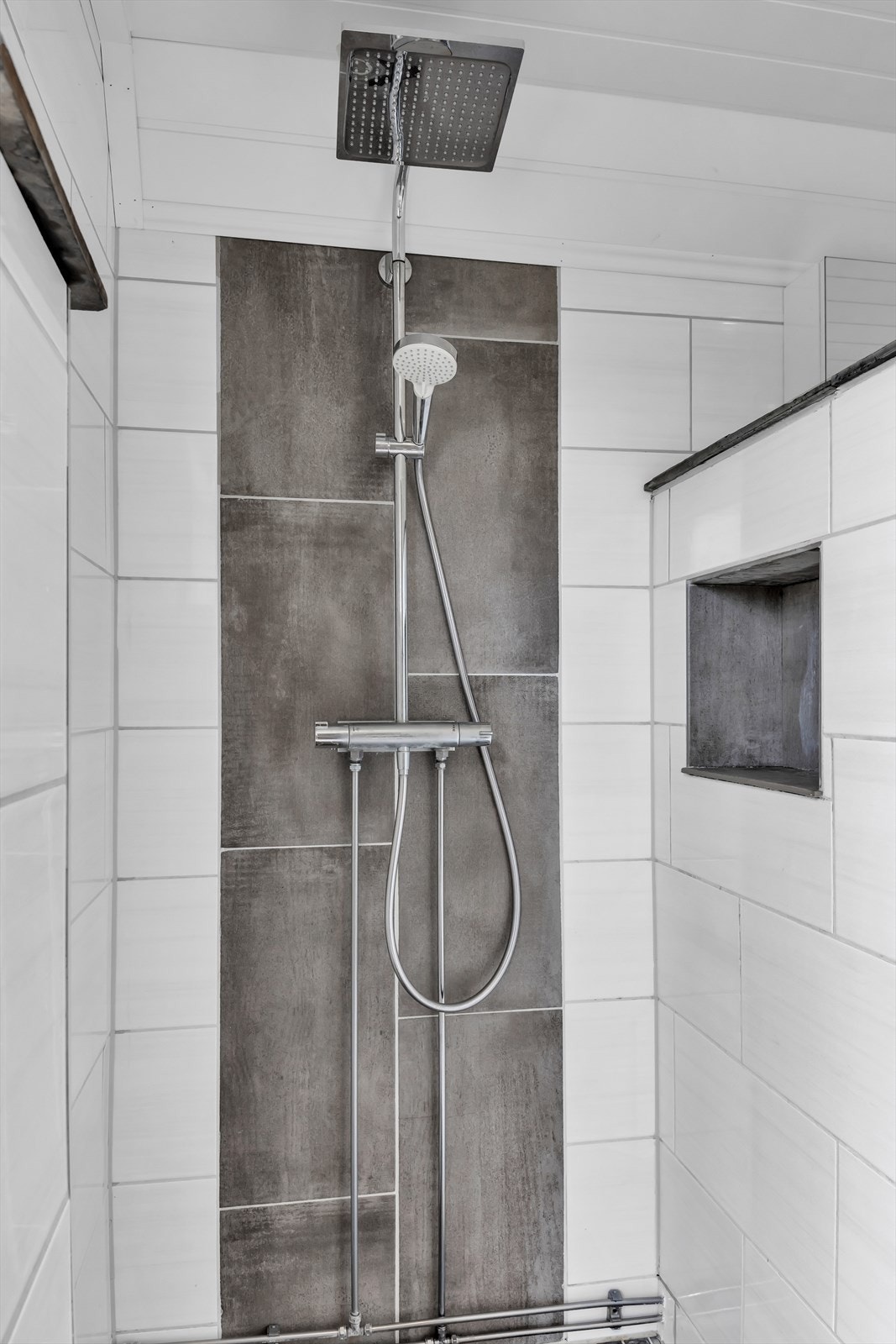 Deler av badets areal er adskilt i en delvis åpen dusjnisje med hånd- og regndusj. Galleribilde