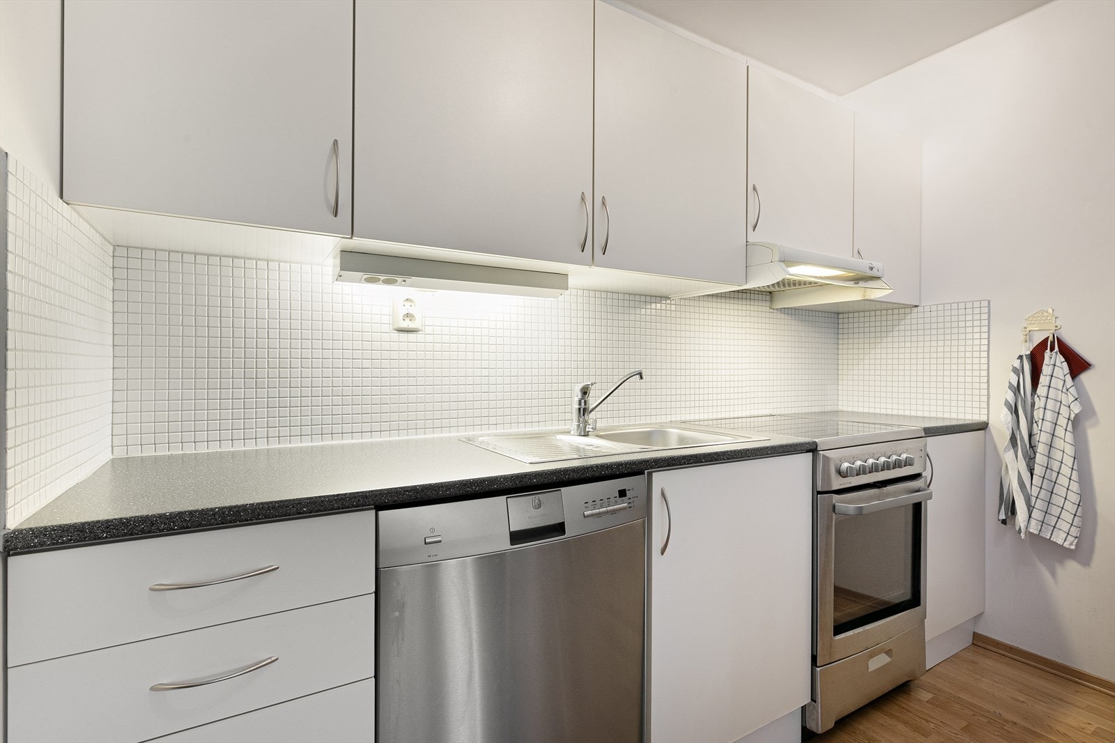 Kjøkkeninnredning fremstår med glatte fronter og laminert benkeplate. Galleribilde