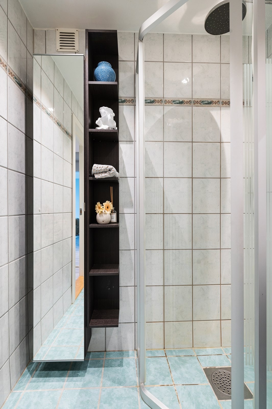 Badet er utstyrt med varmekabler i gulvet, veggmontert toalett, servant med innredning og dusjhjørne med skyvbar glassdør. Galleribilde