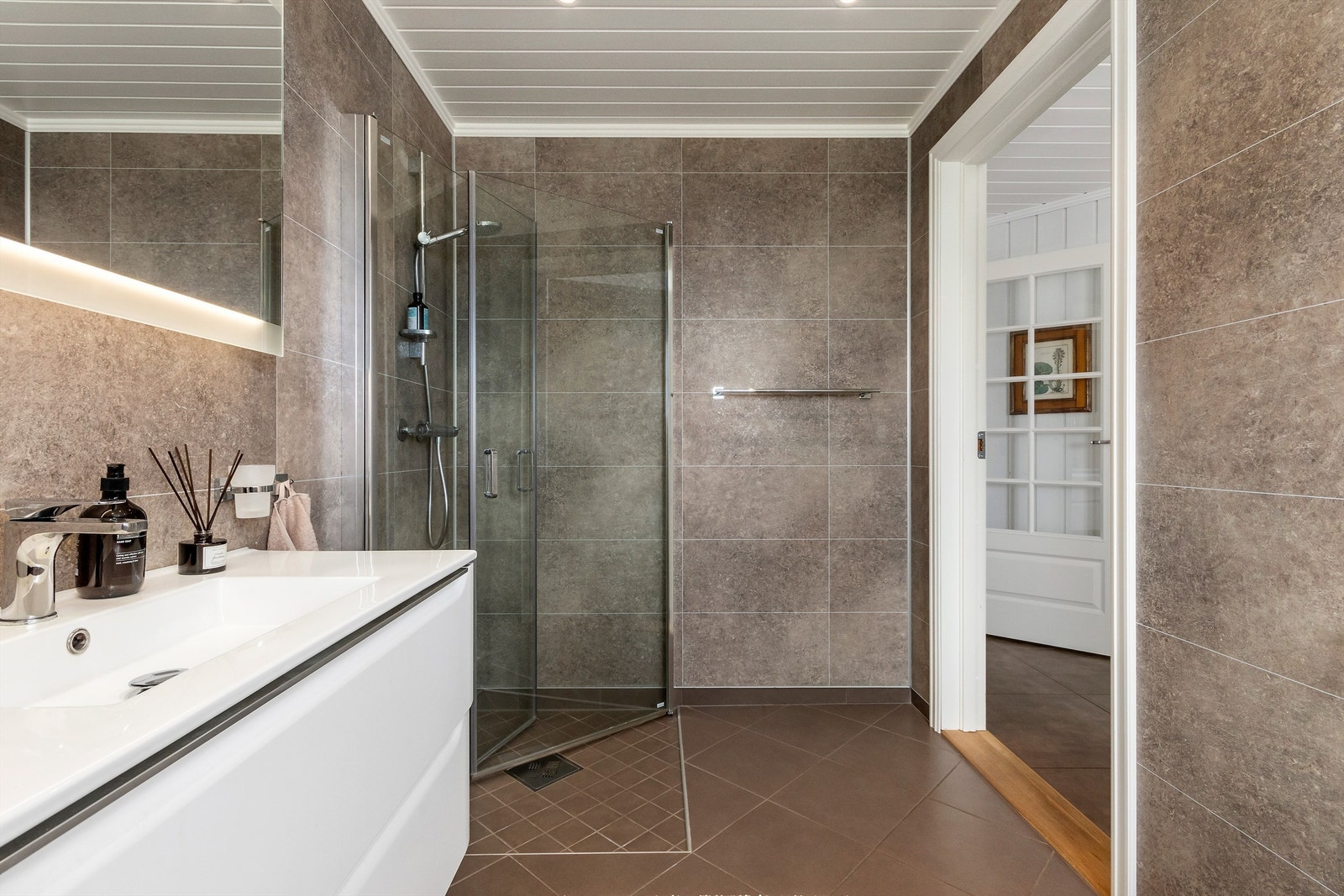 Badet i 1. etasje er fra 2018 med flislagt gulv med gulvvarme og himling med downlights Galleribilde