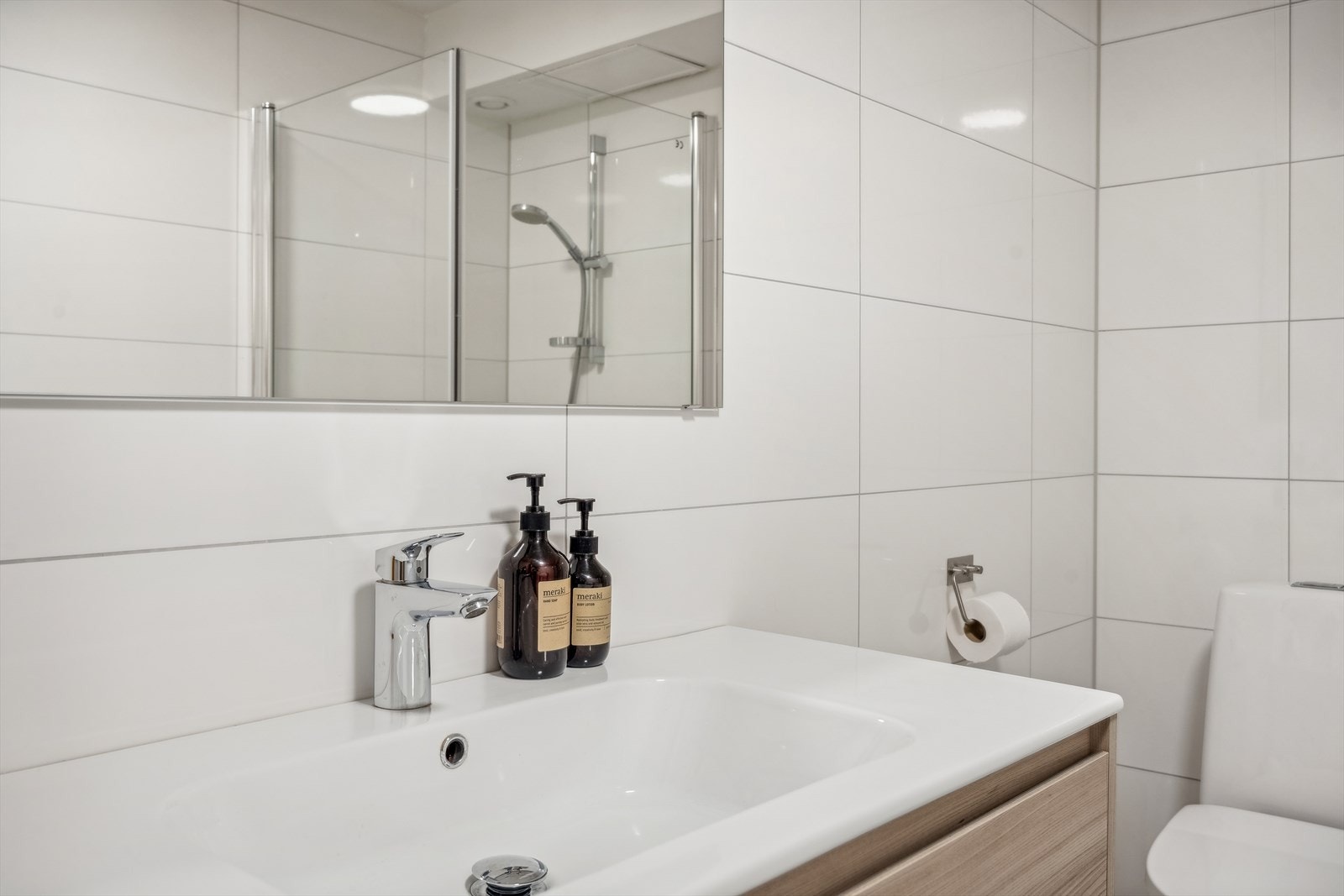 Innredning med skuffer og nedfelt servant, speil, gulvmontert toalett, dusjvegger/hjørne og opplegg for vaskemaskin. Galleribilde