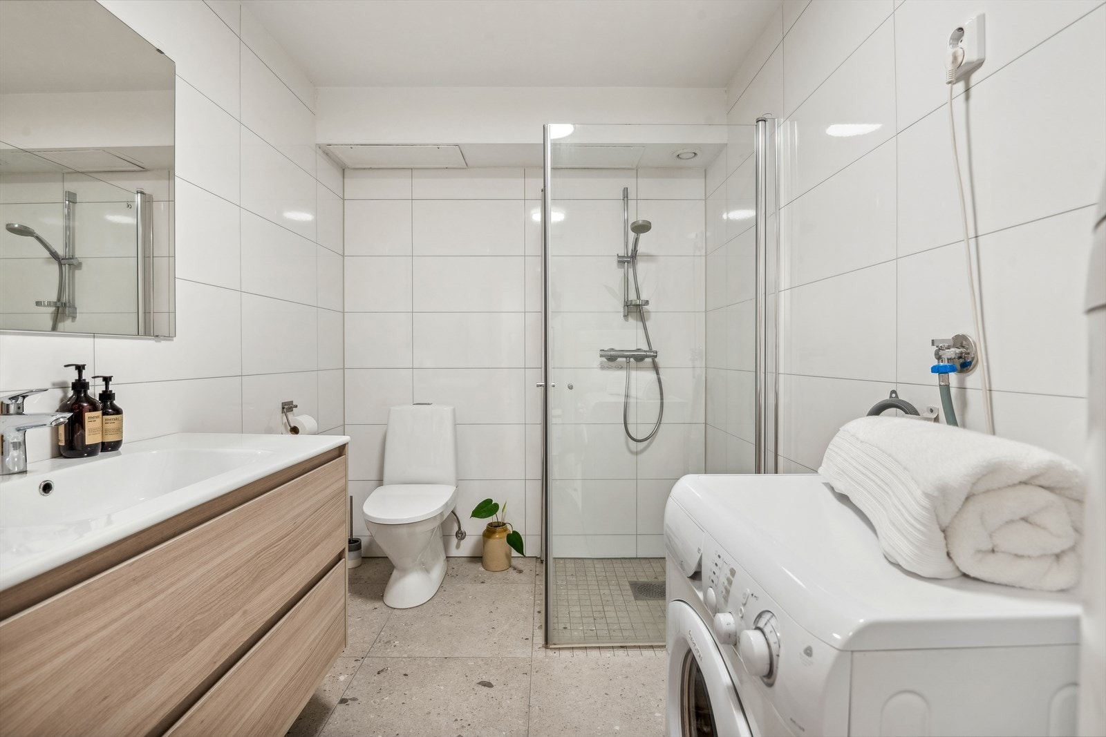 Kombinert bad/vaskerom med delikat flisvalg på gulv og vegger. Galleribilde