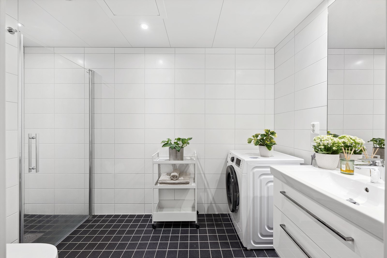 Badet har dusjnisje, vegghengt wc, delikat innredning med vask og opplegg for vaskemaskin. Galleribilde