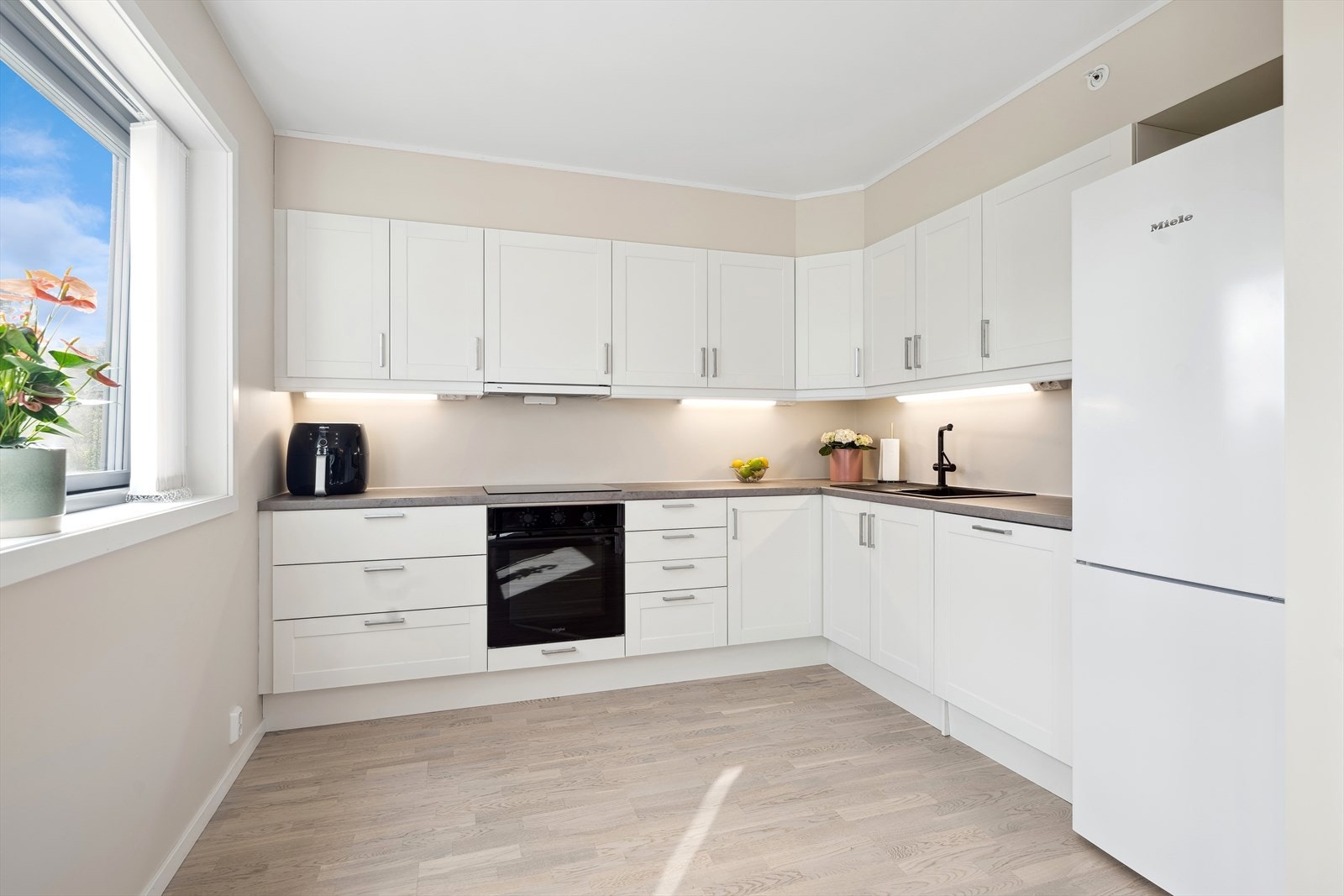 Lyst og lekkert kjøkken med stilren innredning og laminat benkeplate. Hvitevarer medfølger salget Galleribilde