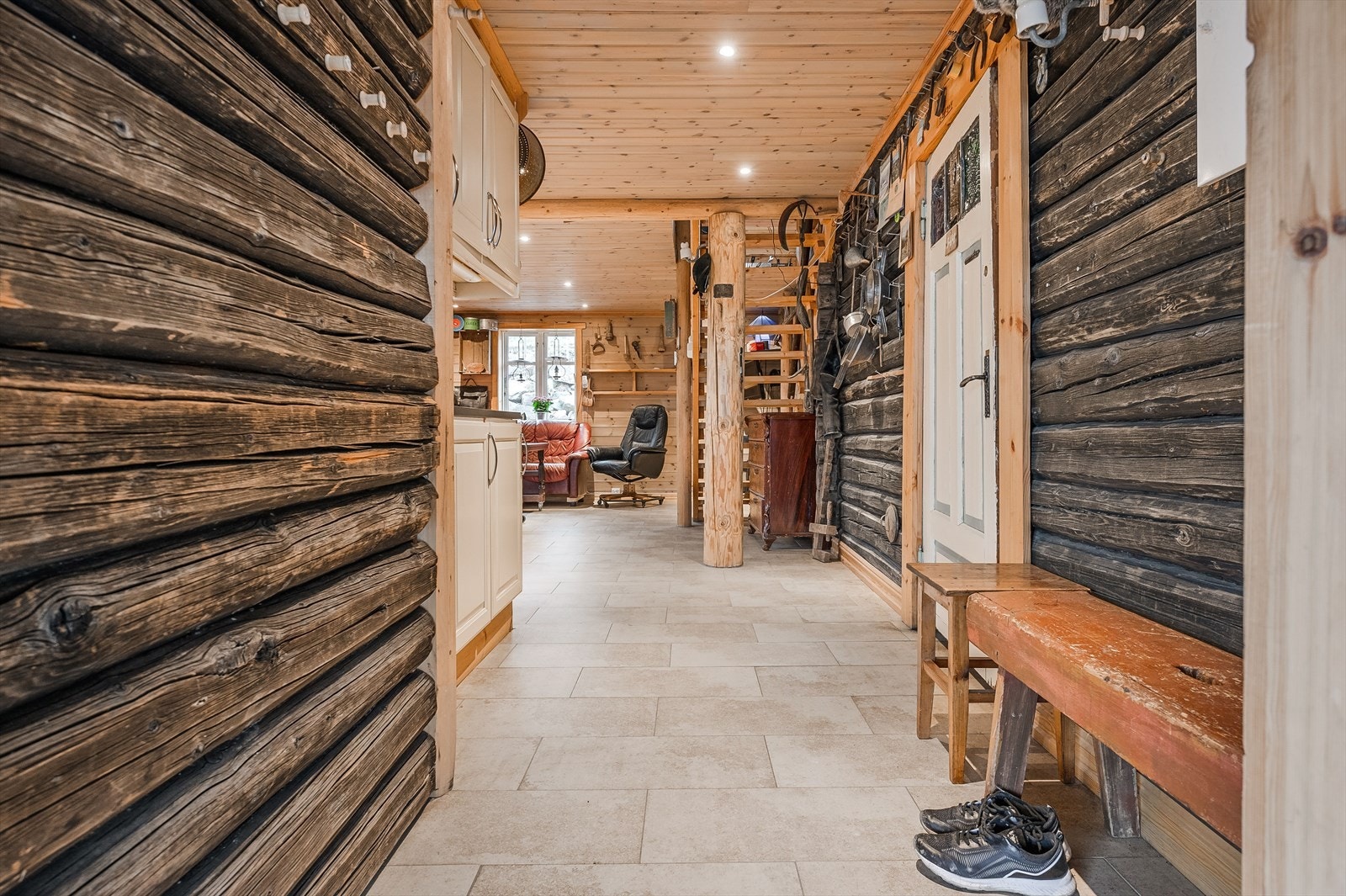 Entréen ar god standard med grå fliser på gulv med vannbåren gulvvarme, overflater med laftet tømmer og downlights i himlingen. Galleribilde