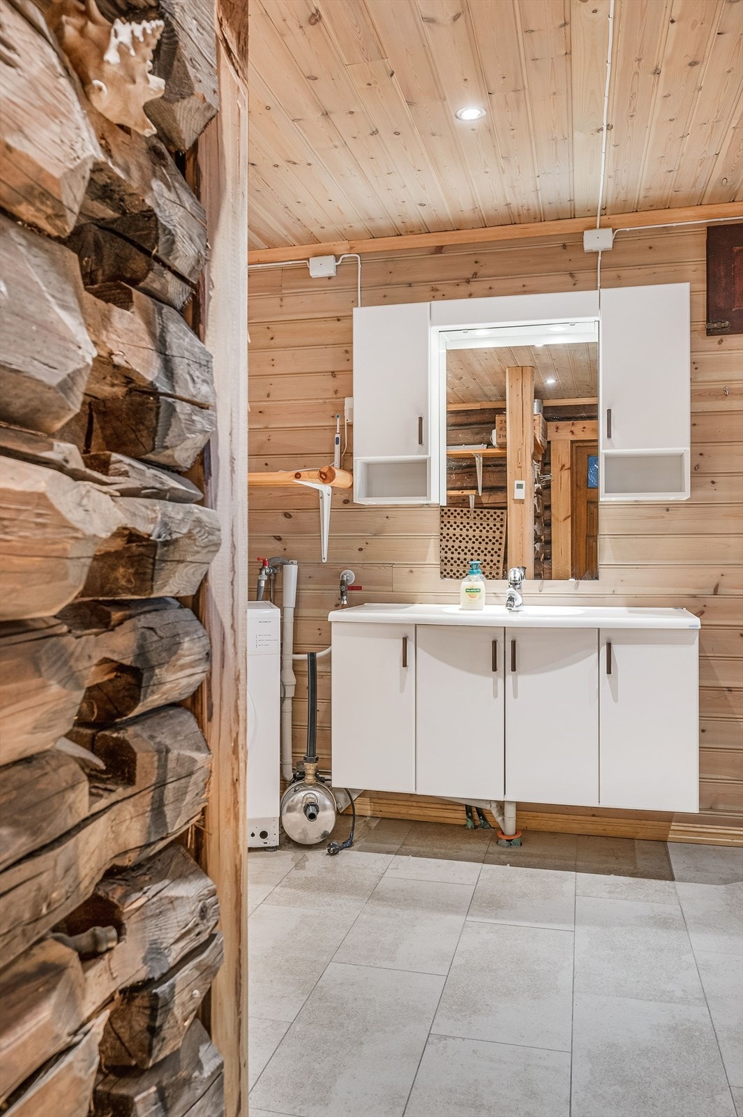 Tidløs baderomsinnredning med lyse fronter og heldekkende servant, speil med belysning og vegghengte skap over. Galleribilde