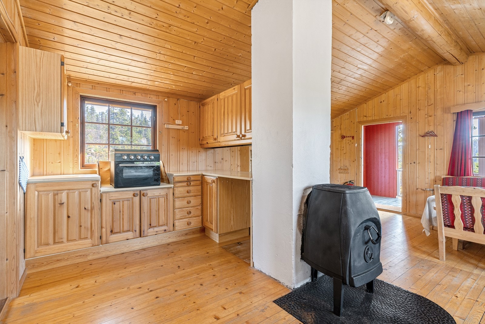 Det er delvis åpen løsning mellom stue og kjøkken. Hytta varmes opp med vedovn som er praktisk plassert midt i rommet. Galleribilde