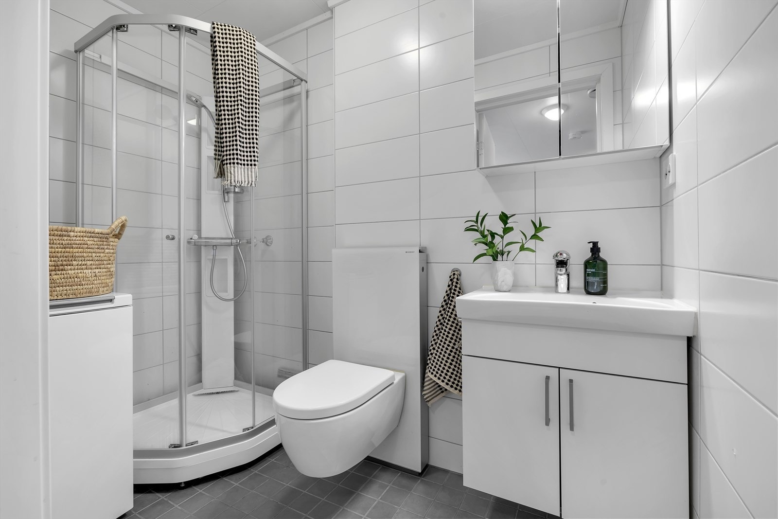 Badrom hybeldel med vegghengt toalett, dusjkabinett og opplegg til vaskemaskin. Galleribilde