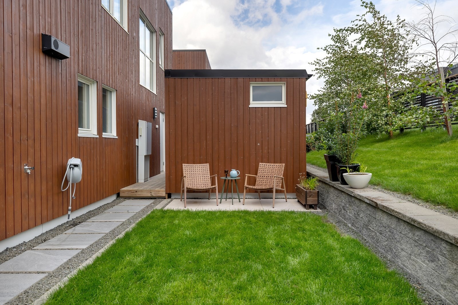 Nydelig liten hage. Legg merke til de flotte steinhellene, den grønne plenen og støttemuren. Her er ting planlagt og gjennomført skikkelig. Galleribilde