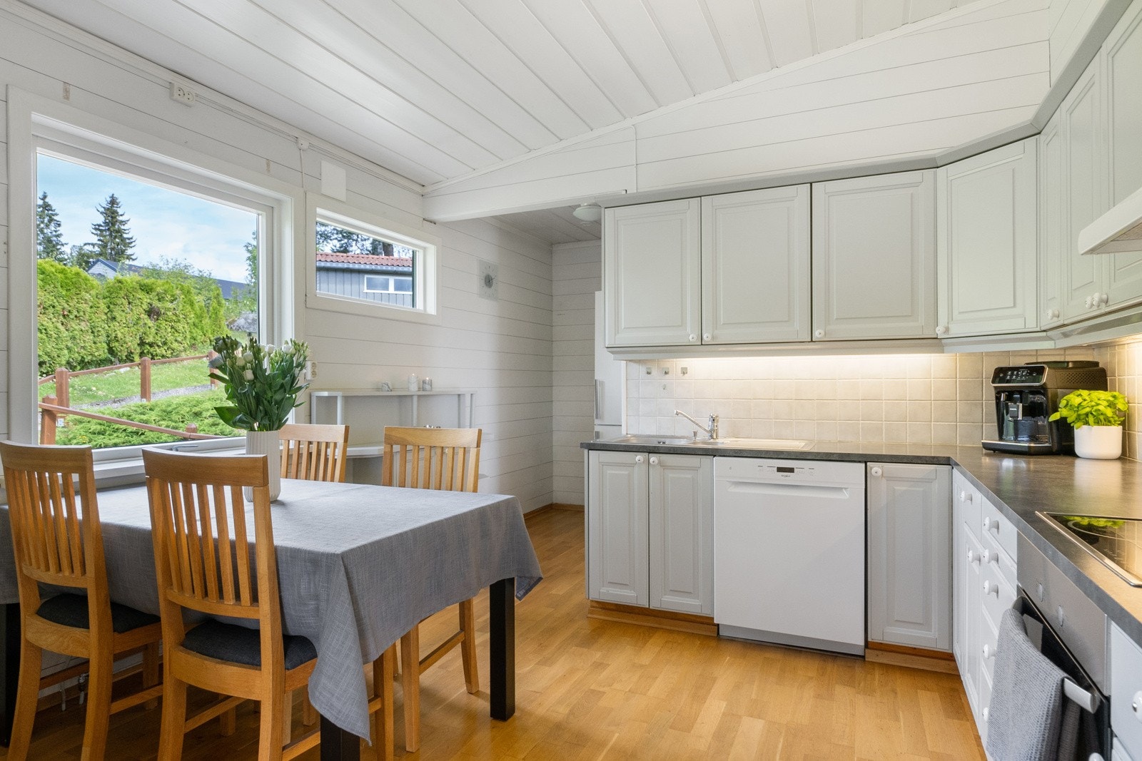 Kjøkken med innredning i vinkel og plass til spisebord. Galleribilde