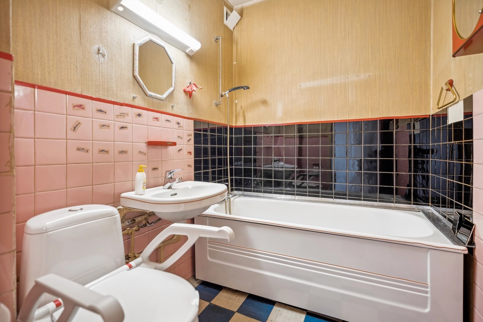 Eldre baderom med vinylbelegg med oppbrett på vegg. Dusj i badekar, servant og gulvstående klosett. Galleribilde