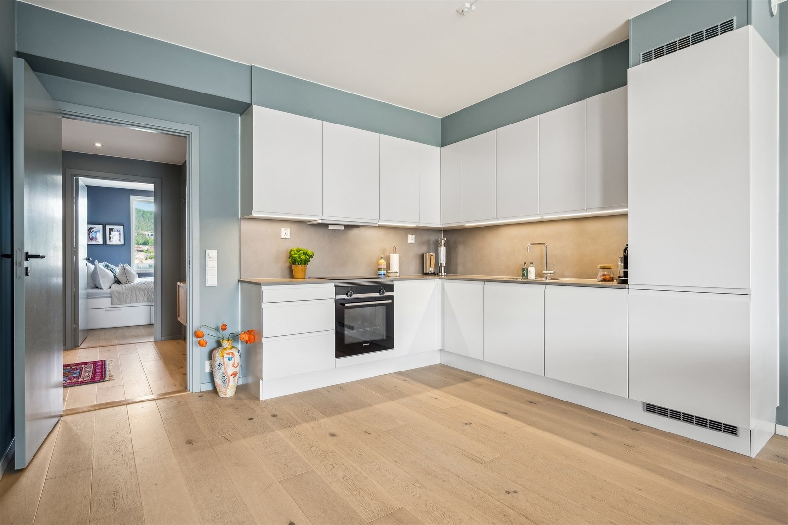 Kjøkkenet fremstår som tidsriktig og stilrent med lyse og glatte fronter. En god kombinasjon av skap og skuffer gir mye oppbevaringsplass og gode arbeidsflater. Galleribilde