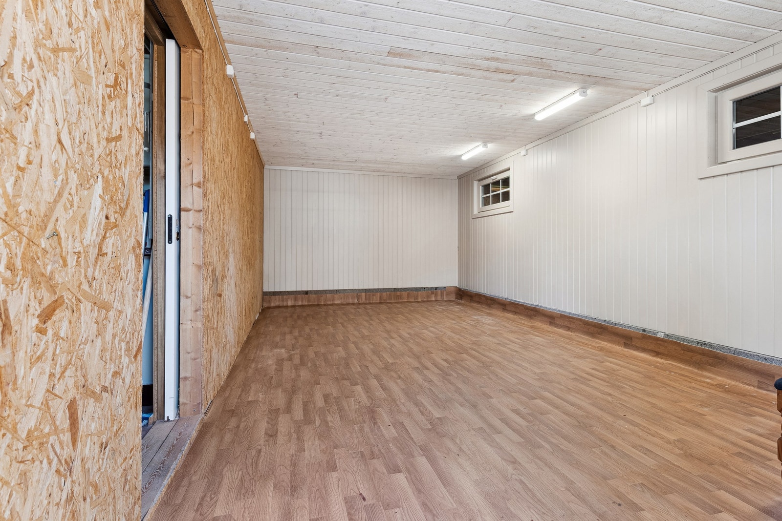 Garasjen har også et praktisk innredet rom med mdf- veggplater og belegg på gulv. Rommet er fint til ekstra oppbevaring. Galleribilde