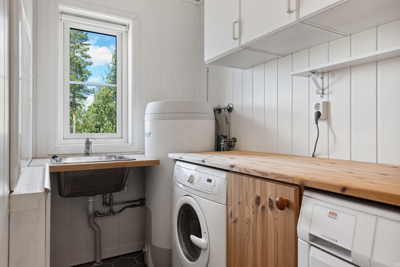 Vaskerom med praktisk benkeinnredning, veggskap og vaskekum. Oppegg for både vaskemaskin og tørketrommel. Galleribilde