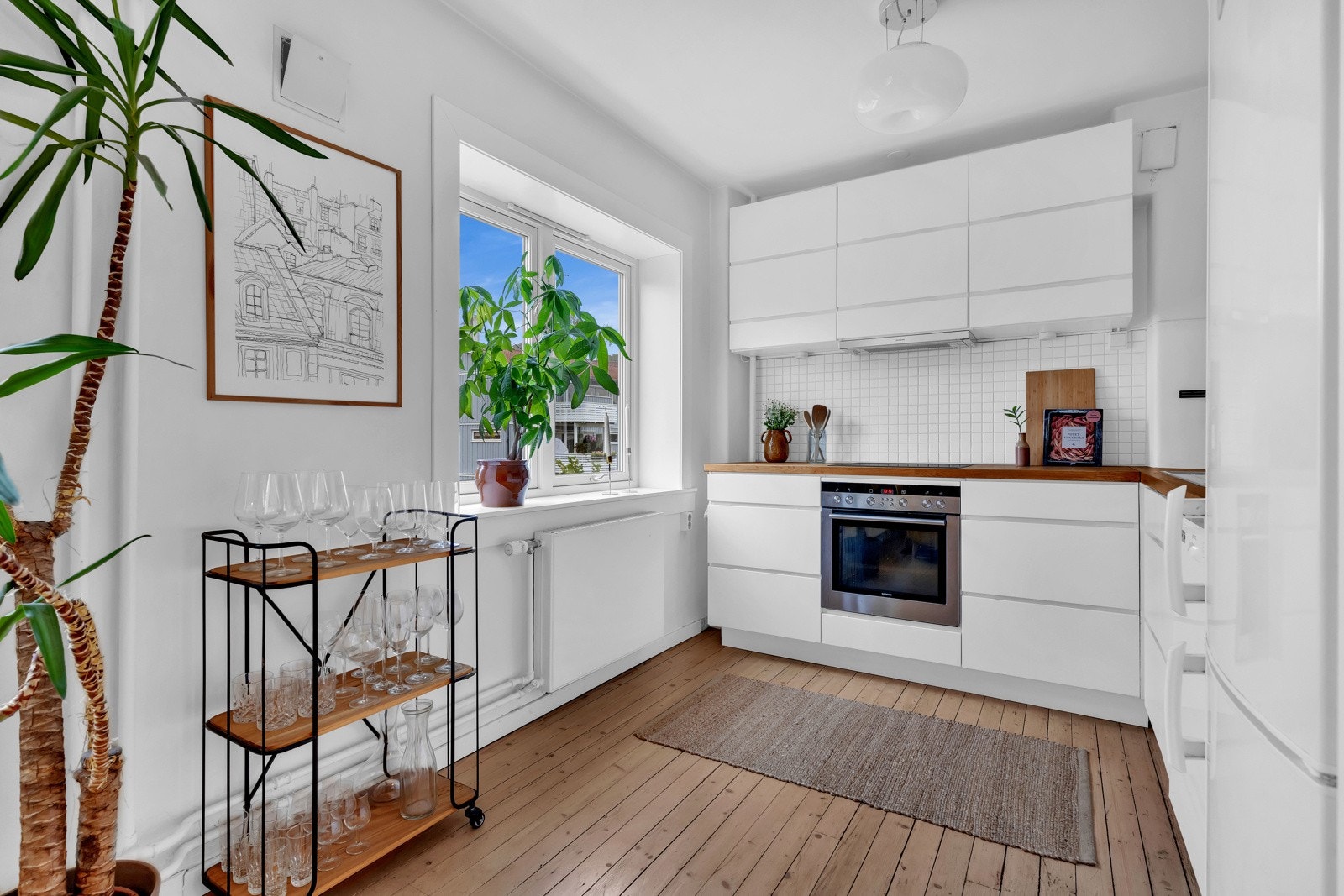 Rommet har malte vegger og originale tregulv. Kjøkkeninnredningen har hvite glatte fronter som gir rommet et moderne og rent utrykk. Galleribilde
