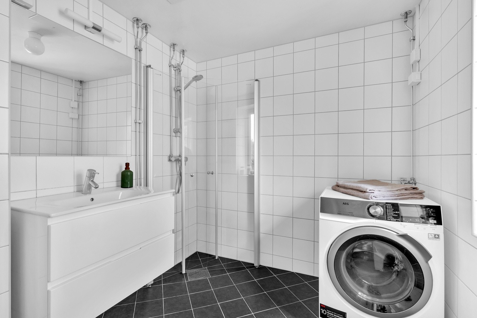 Baderommet har adkomst fra soverommet og er innredet med vegghengt servantskap, dusjhjørne med glassdører og opplegg for vaskemaskin. Badet ble oppgradert i regi av borettslaget i 2010. Galleribilde