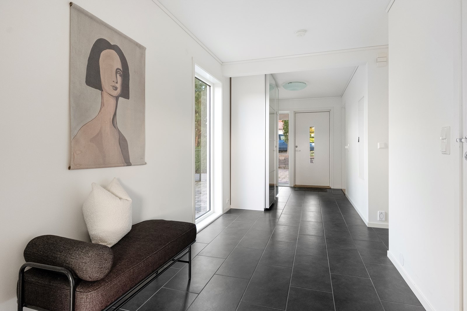 Romslig flislagt entrè med garderobeløsning. Galleribilde