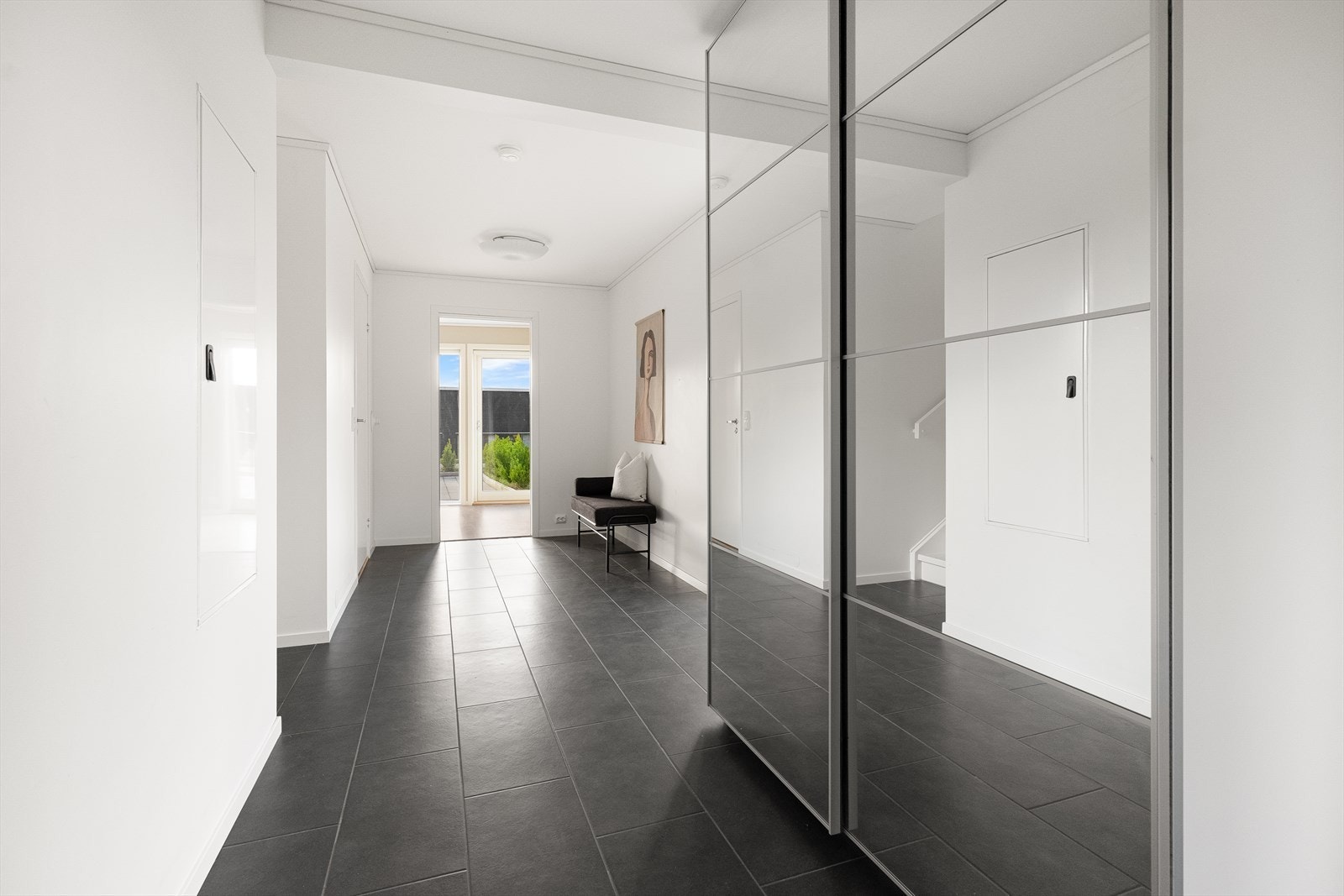 Lys og romslig entré med store speilflater og flislagt gulv, som gir et moderne og innbydende førsteinntrykk. Galleribilde