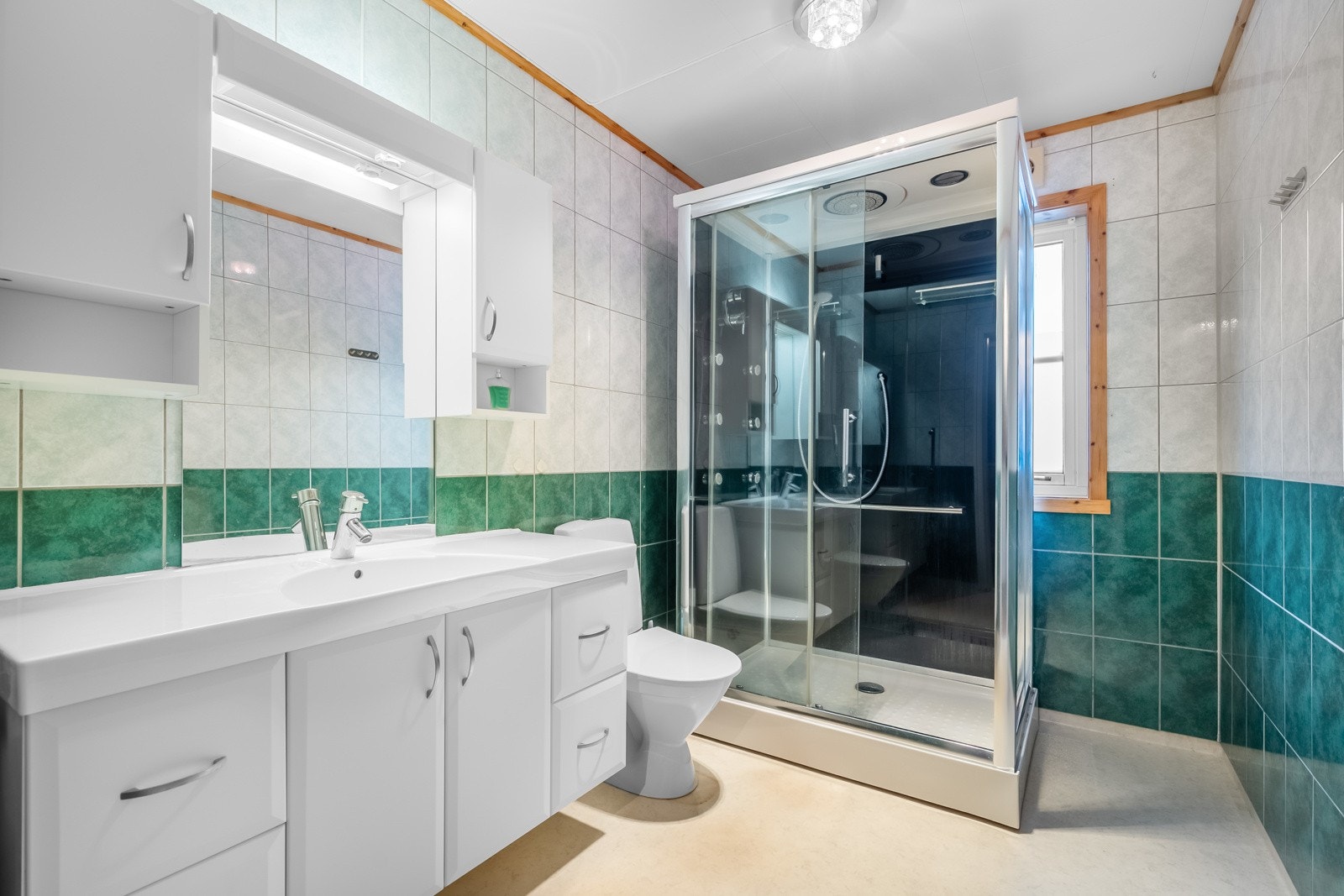 Stort baderom bestående av servant med underskap, toalett og dusjkabinett Galleribilde