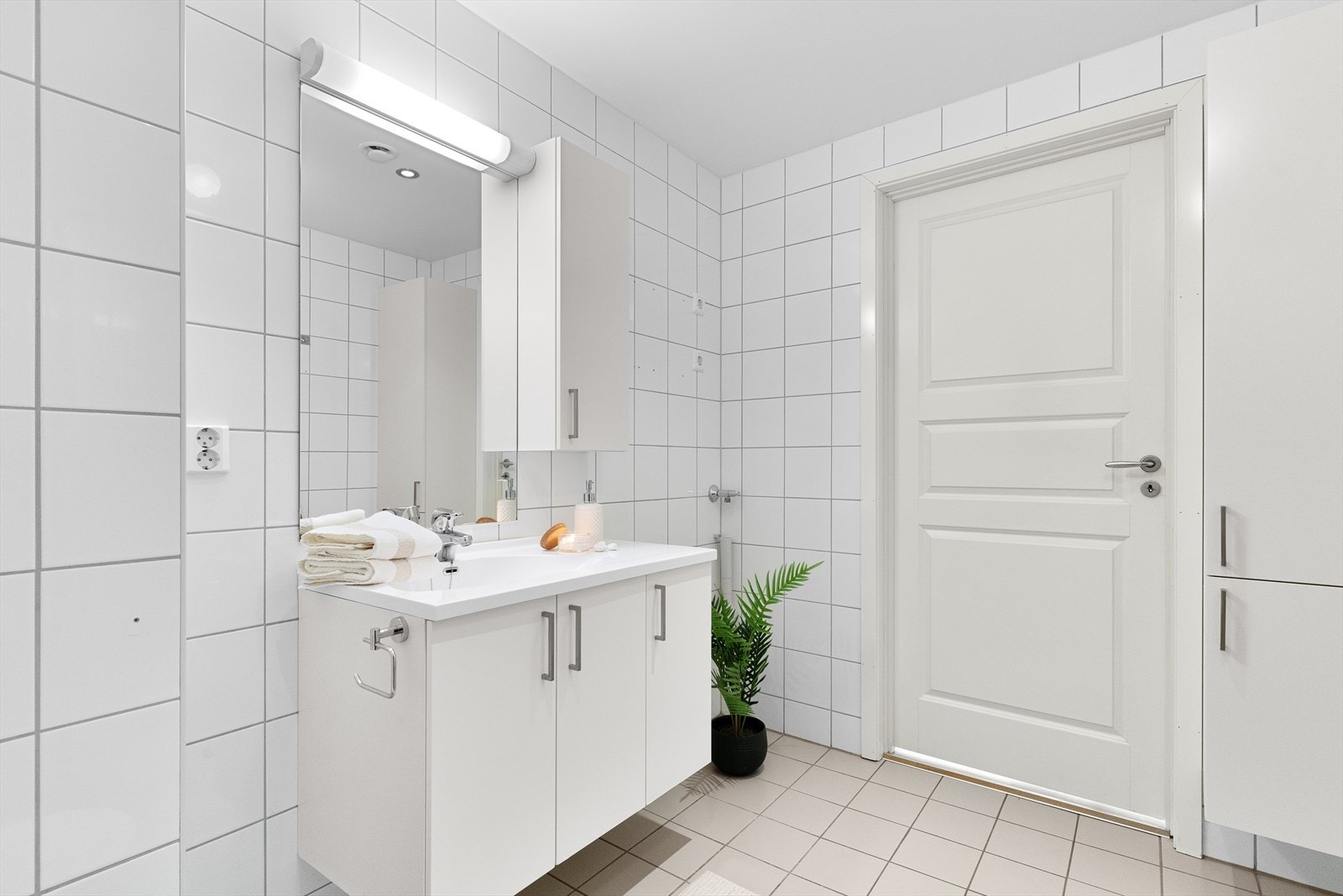 Rommet har en praktisk innredning med nedfelt servant, vegghengt toalett og et dusjhjørne med svingbare glassdører, samt opplegg for vaskemaskin. Galleribilde