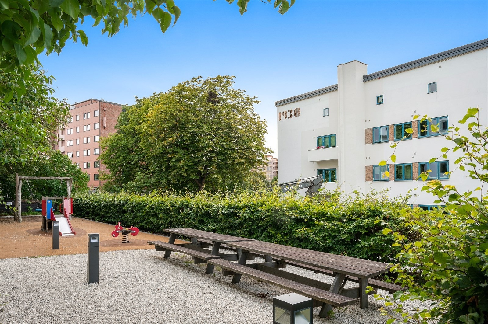 Koselig bakgård opparbeidet med sittebenker og lekeapparater. Galleribilde
