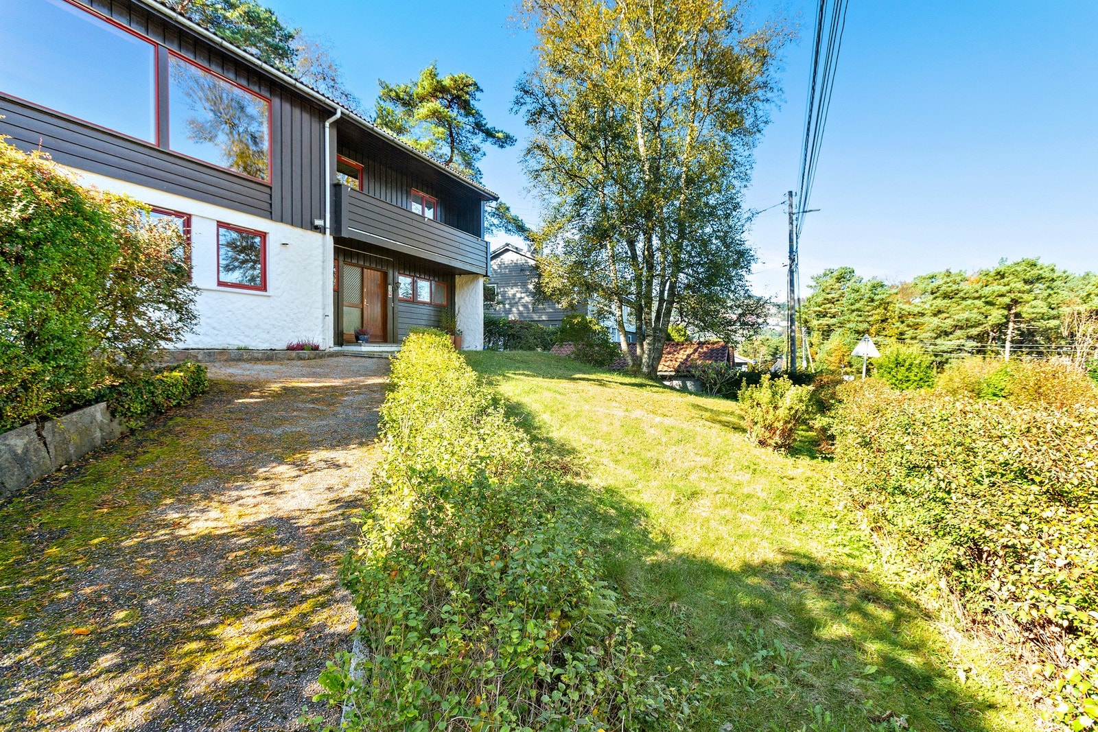 Asfaltert innkjørsel og gressplen i front av boligen Galleribilde