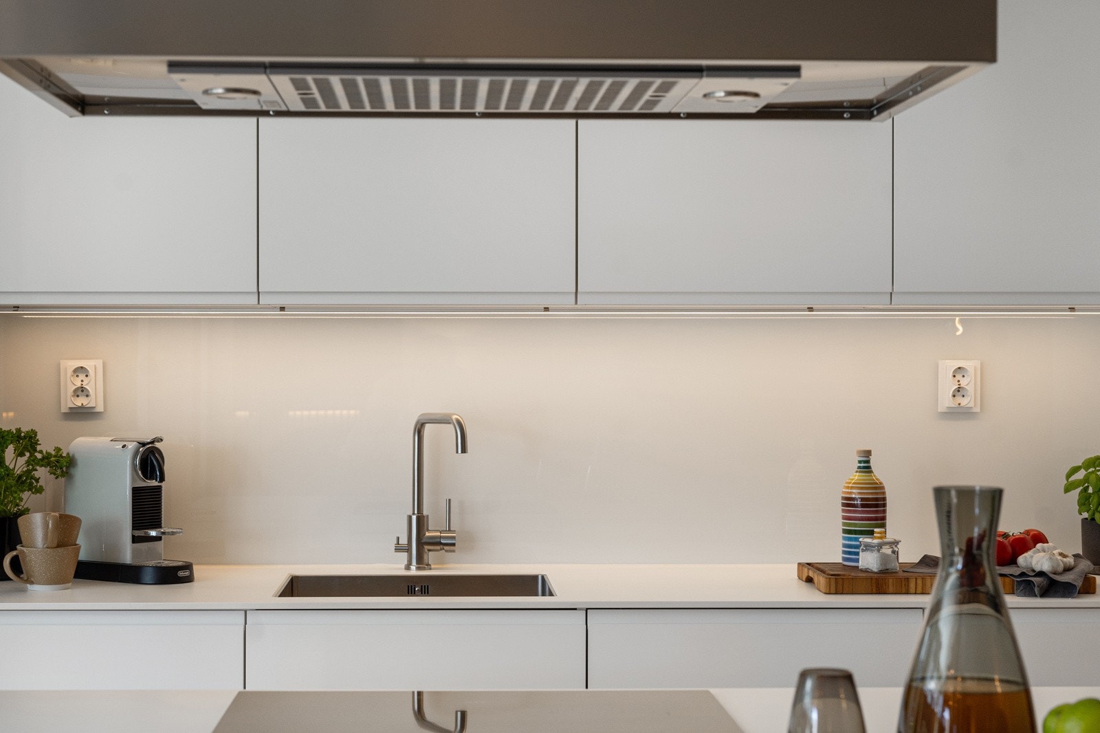 Kjøkkenet har moderne innredning med slette hvite fronter og integrerte hvitevarer. Galleribilde