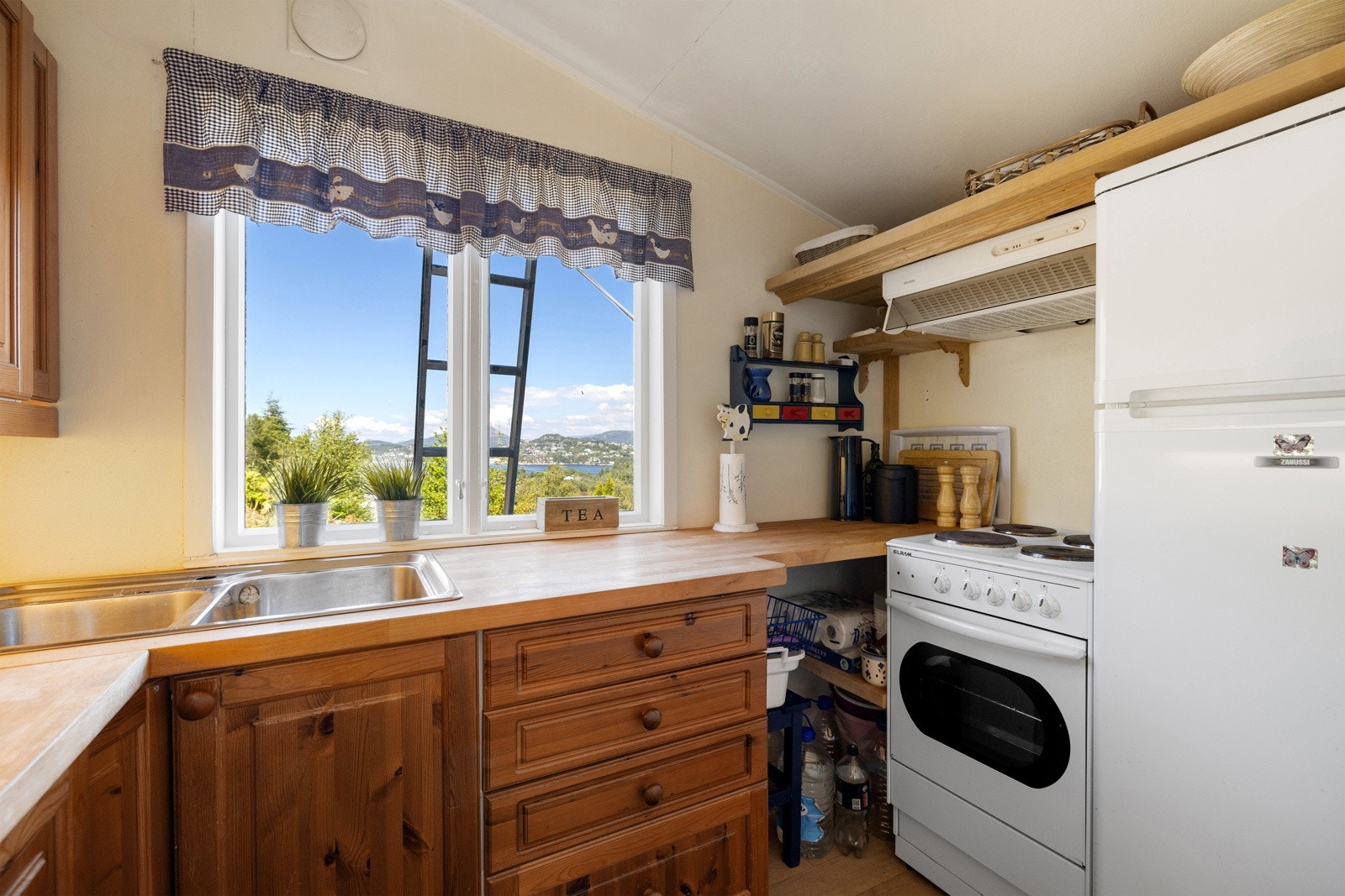 Kjøkkenet er arealeffektivt og gir plass til kjøleskap, komfyr, benkeplate og nok med skap- og hylleplass. Her kan kokken kokkelere med nydelig utsikt forut Galleribilde