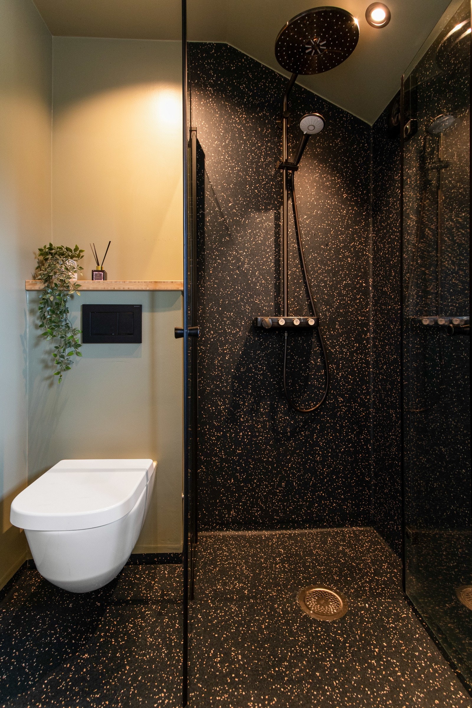 Badet er innredet med mørkspettet vinylbelegg på gulv og på vegg i dusjen, kombinert med slette, malte veggflater, downlights i taket og varme i gulvet. Galleribilde