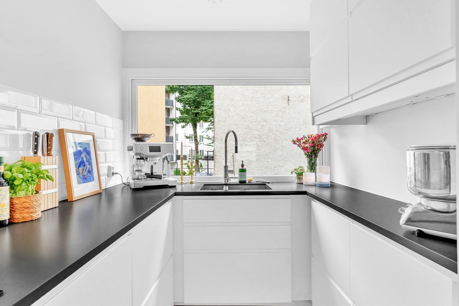 Med sitt stilige utseende, preget av skapfronter med hvite, glatte fronter og en mørk steinbenkeplate, er kjøkkenet både funksjonelt og estetisk tiltalende. Galleribilde