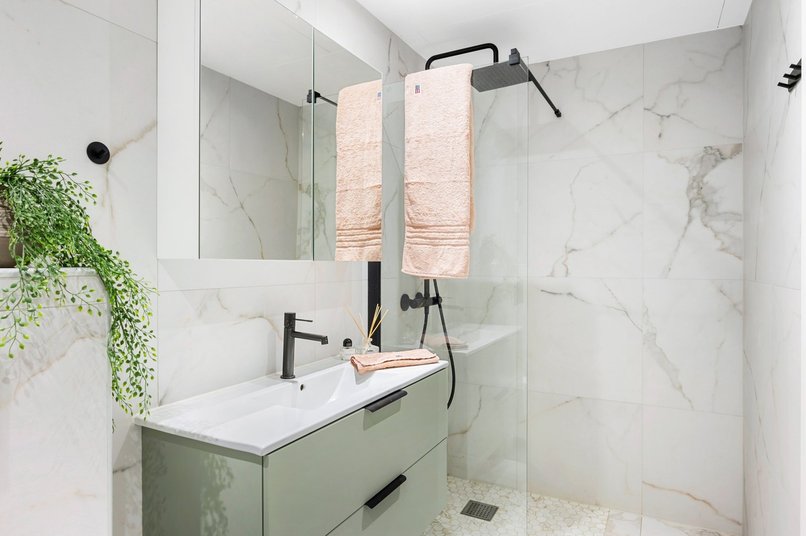 De store keramiske flisene med marmorutseende sammen med de svarte detaljene gir badet et eksklusivt preg. Galleribilde