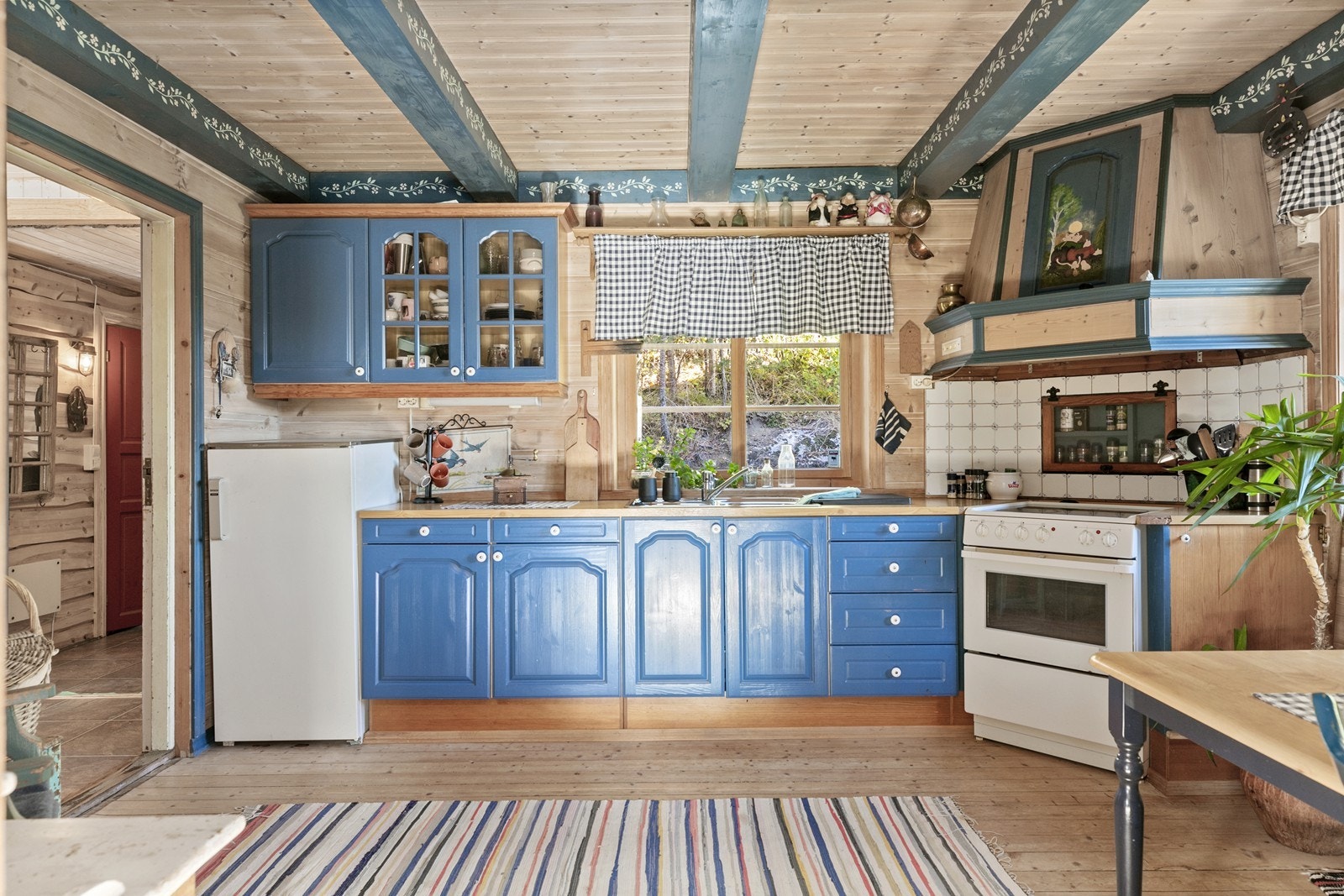 Kjøkkenet er romtilpasset med bl.a malte profilerte fronter, laminatbenkeplate og nisje for komfyr og kjøleskap. Galleribilde