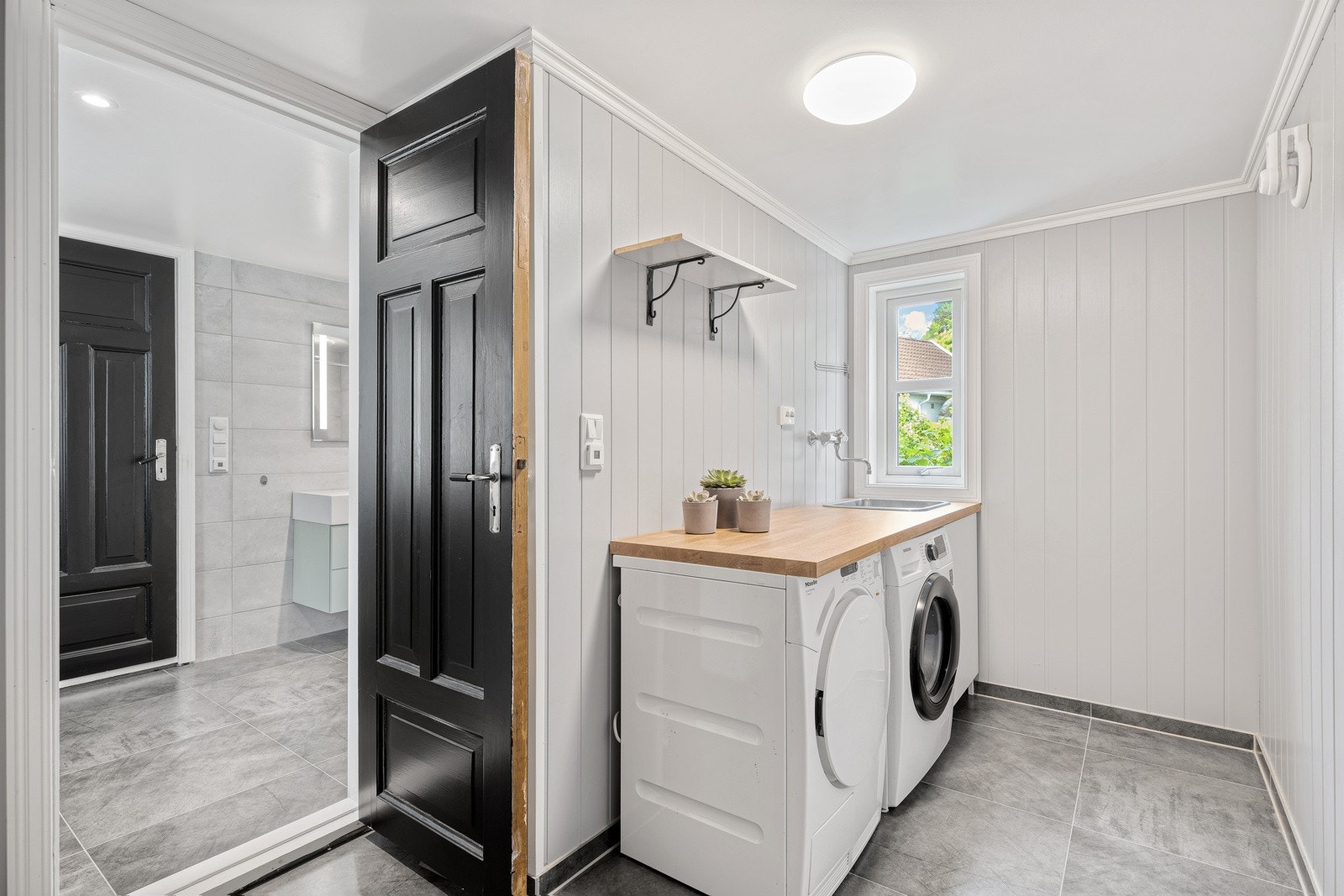 Innenfor badet har boligen et eget vaskerom med gulvvarme og hendig innredning. Galleribilde