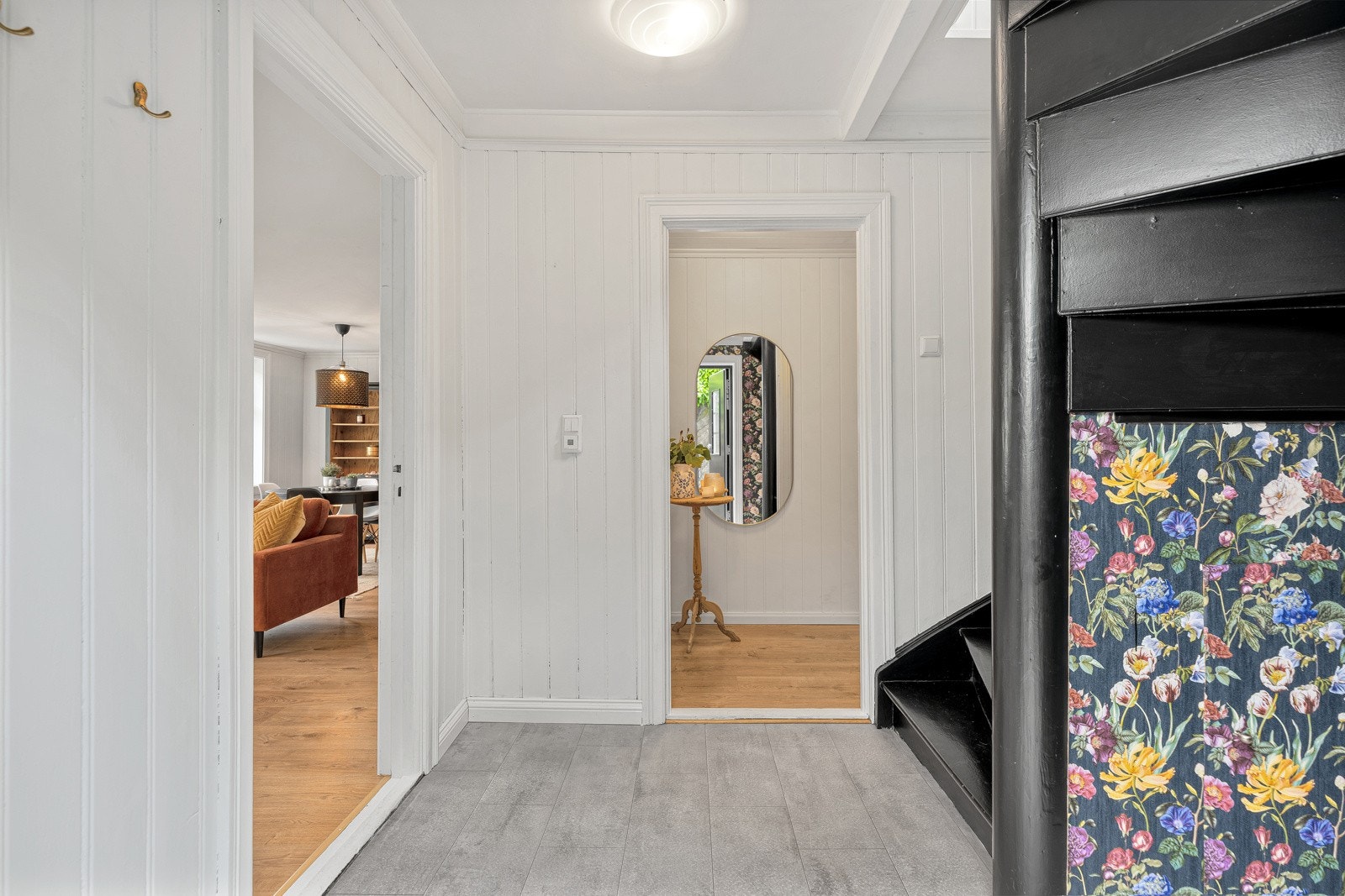 Entreen er innredet med flislagt gulv og en stilig kontrastvegg kledd i blomstret tapet. Praktisk tilliggende rom til plassering av tøy og sko Galleribilde