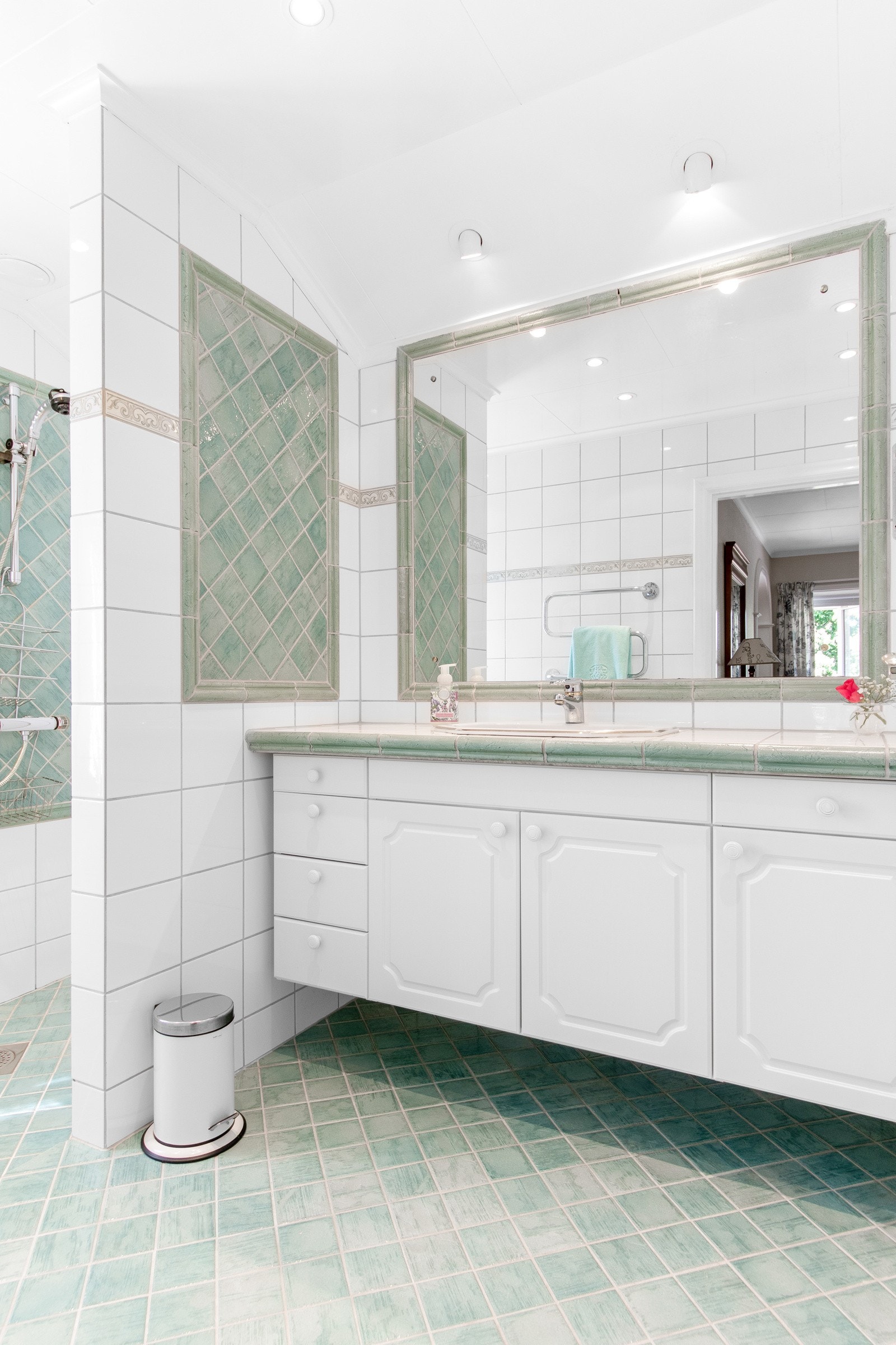 Badet har en flislagt dusjnisje og en flislagt, bred benkeplate med nedfelt servant. Under benken er det flere skap, og over er det et innfliset speil og spotbelysning. Badet har varmekabler. Galleribilde