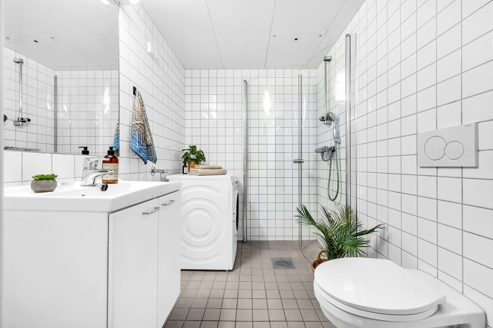 Stort bad fra byggeår med flislagte overflater, elektrisk gulvvarme og opplegg for vaskemaskin. Galleribilde