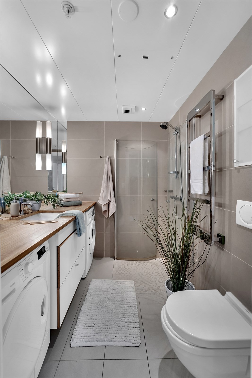 Badet har dusjhjørne, vegghengt wc, stort speil og servant med skuffer. Galleribilde