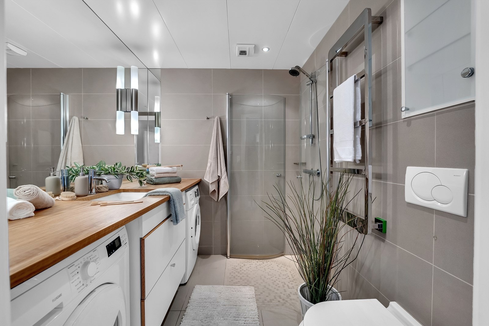 Delikat flislagt bad med vaskemaskin og tørketrommel som medfølger i handelen. Galleribilde