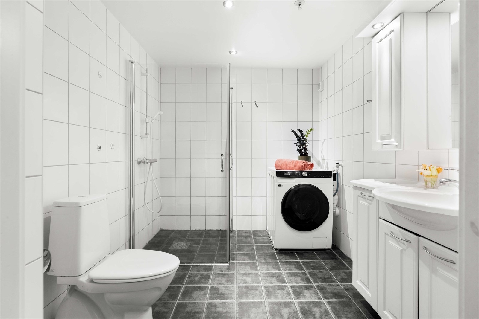 Flislagt bad med gulvvarme, innsvingbare dusjdører, downlights i tak og opplegg for vaskemaskin. Galleribilde